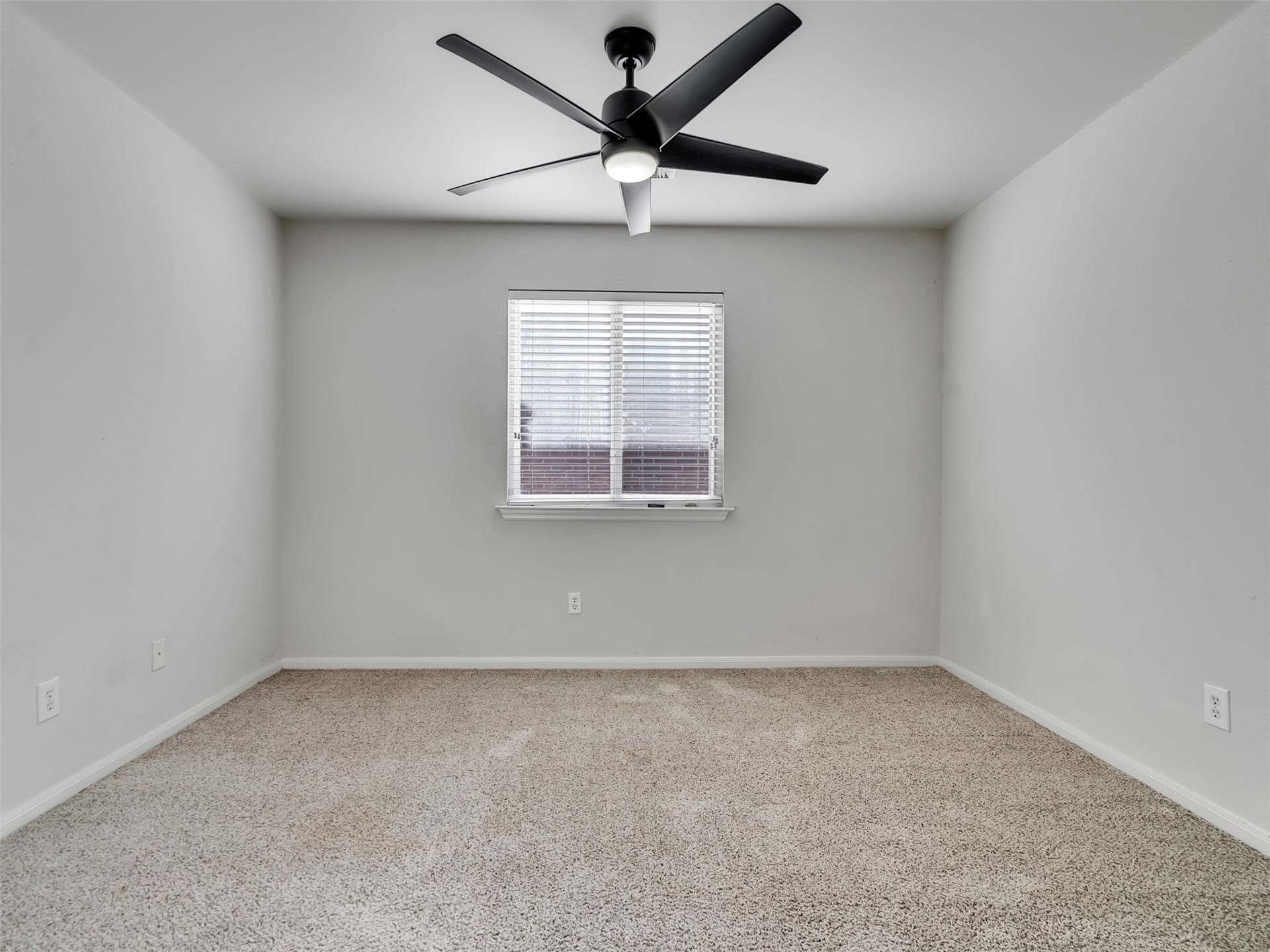 21518 Gannet Peak Way, Katy, TX 77449 This is a cozy, carpeted room featuring neutral walls, a central window with blinds, and a modern ceiling fan, ideal for a bedroom or office space.
