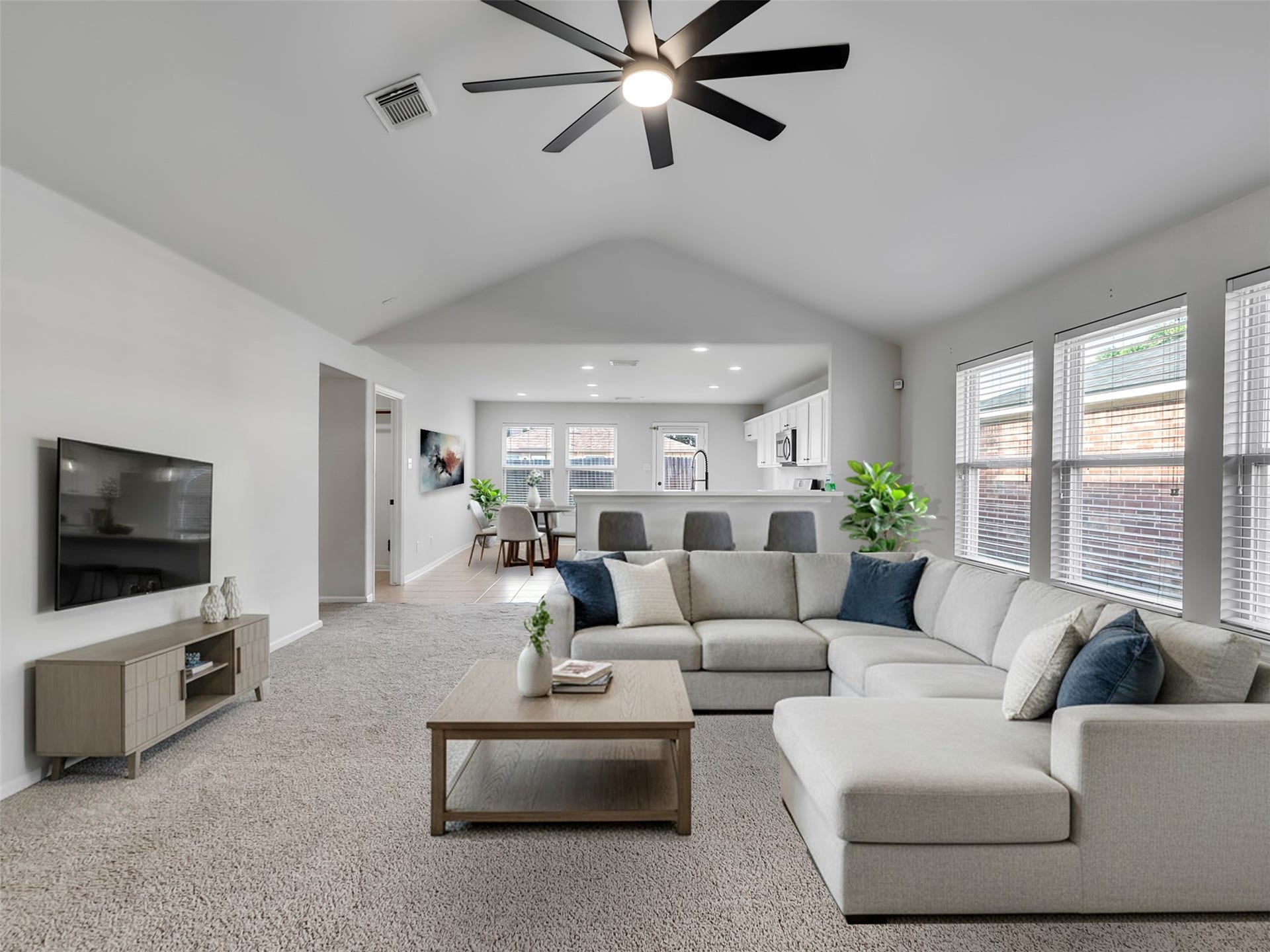 21518 Gannet Peak Way, Katy, TX 77449 This spacious living area features vaulted ceilings, ample natural light from large windows, and an open layout. It includes a cozy sectional sofa, a modern ceiling fan, and seamless flow into the dining and kitchen areas, ideal for entertaining.