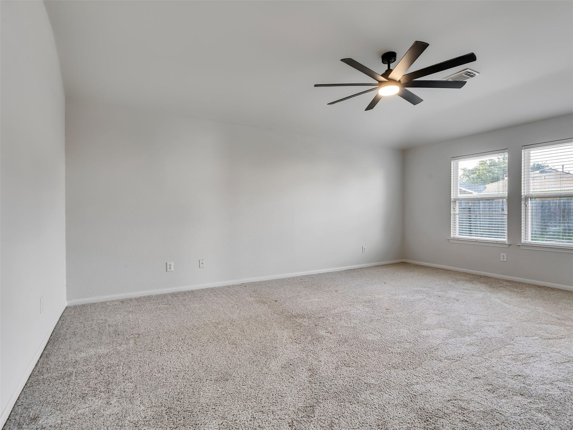 21518 Gannet Peak Way, Katy, TX 77449 This spacious room features neutral carpeting, a modern ceiling fan, and ample natural light from large windows, perfect for a cozy and inviting atmosphere.