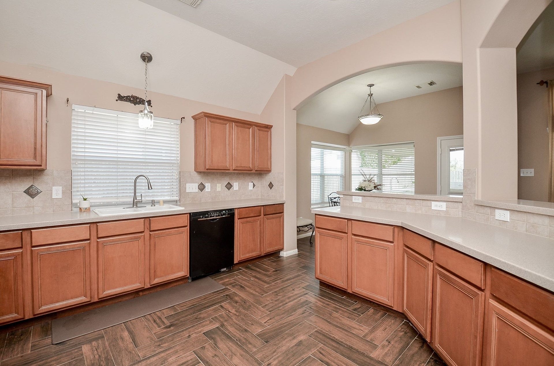 3706 Cane Lake Drive, Richmond, TX 77406 Spacious kitchen with elegant wooden cabinetry, sleek countertops, and a stylish tile floor, featuring a large window for natural light and an open view into the dining area.