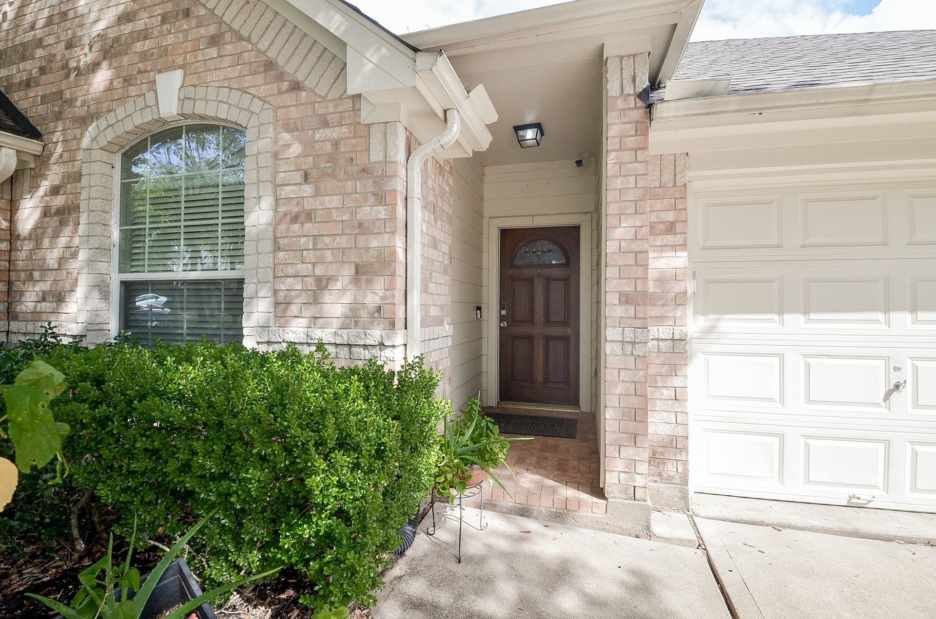 3706 Cane Lake Drive, Richmond, TX 77406 Charming brick exterior with inviting entryway, complemented by lush greenery and a classic garage door.