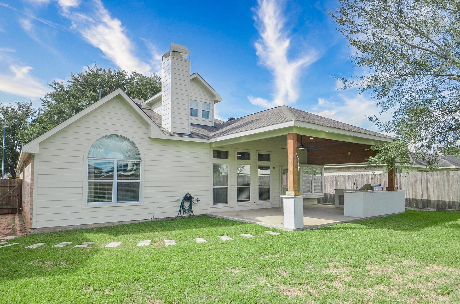 3706 Cane Lake Drive, Richmond, TX 77406 Charming backyard features a spacious covered patio with a built-in outdoor kitchen, perfect for entertaining, set against a backdrop of lush green lawn.