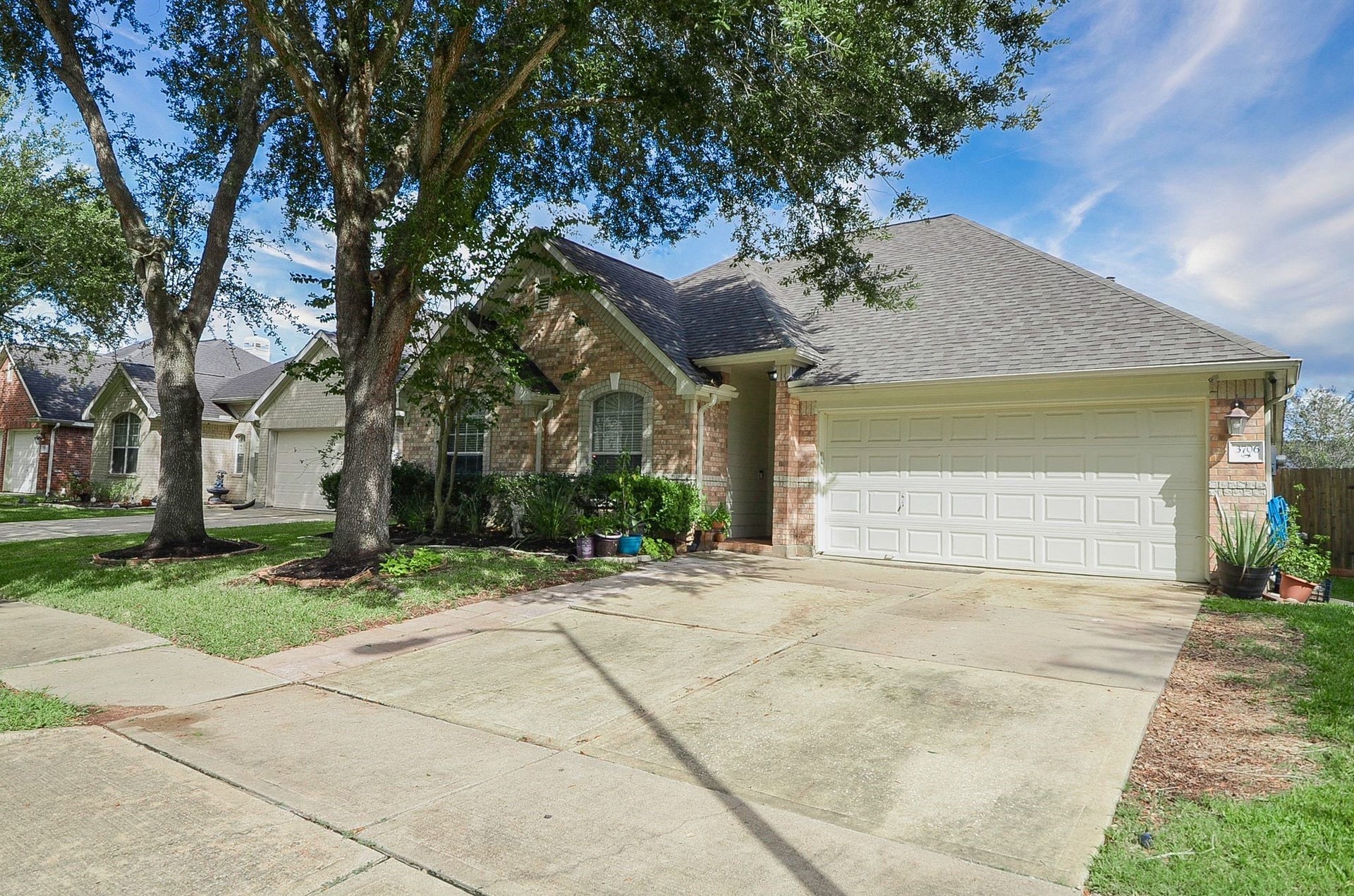 3706 Cane Lake Drive, Richmond, TX 77406 Charming brick home with a spacious two-car garage, nestled among mature trees and featuring a well-maintained front yard.