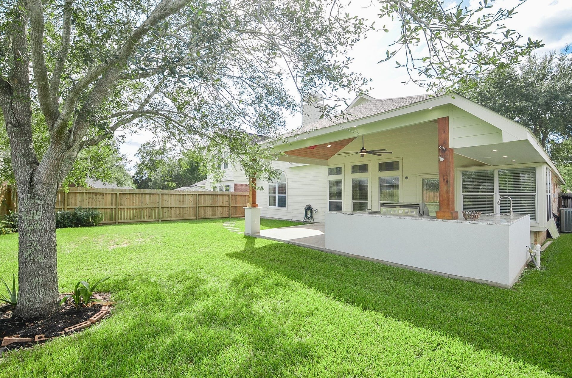 3706 Cane Lake Drive, Richmond, TX 77406 Charming backyard with a spacious covered patio, ceiling fans, and lush green lawn, perfect for outdoor entertaining and relaxation.