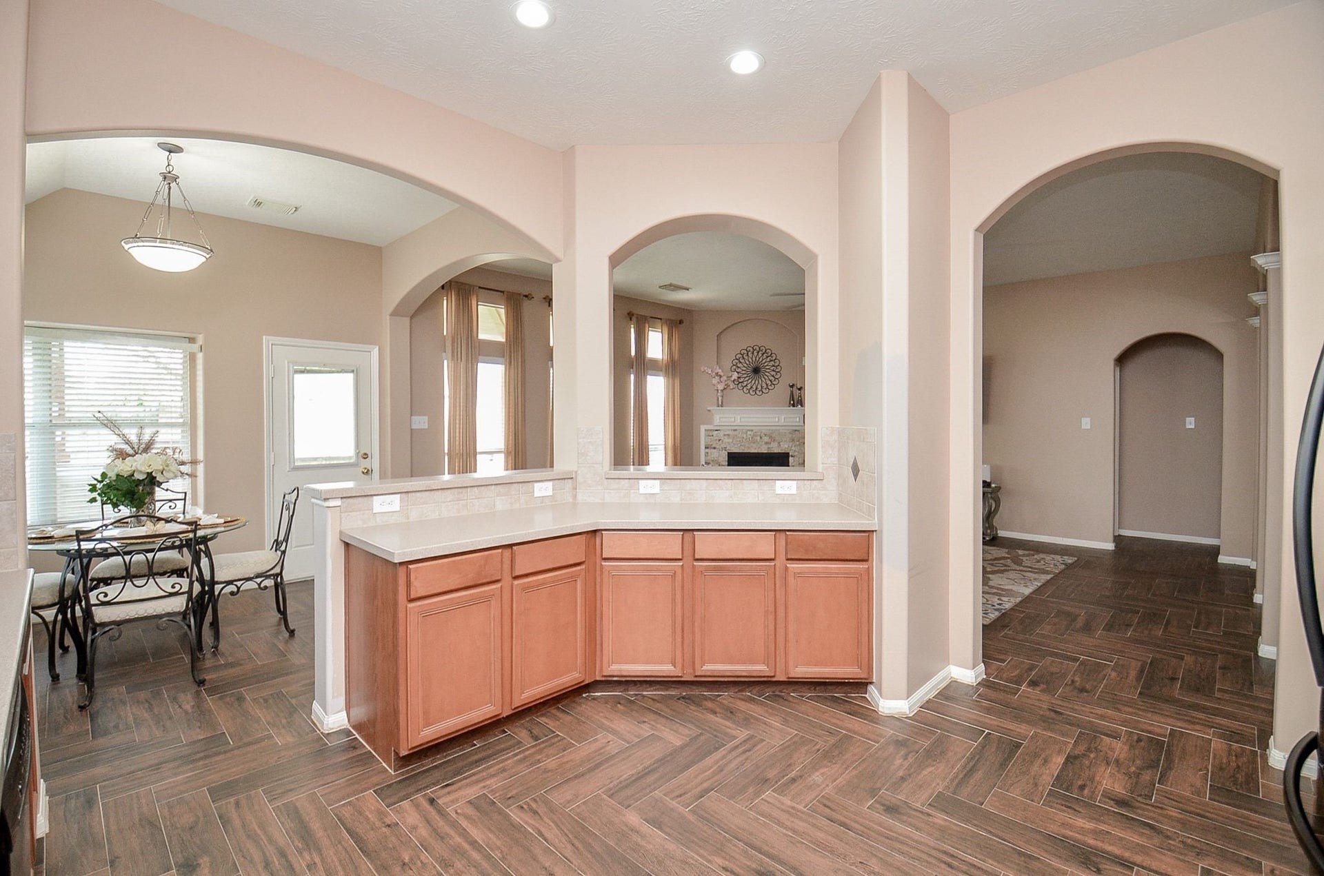 3706 Cane Lake Drive, Richmond, TX 77406 Spacious kitchen with elegant archways, featuring warm wood cabinetry and a sleek tile floor, seamlessly connecting to a cozy dining area and inviting living room.