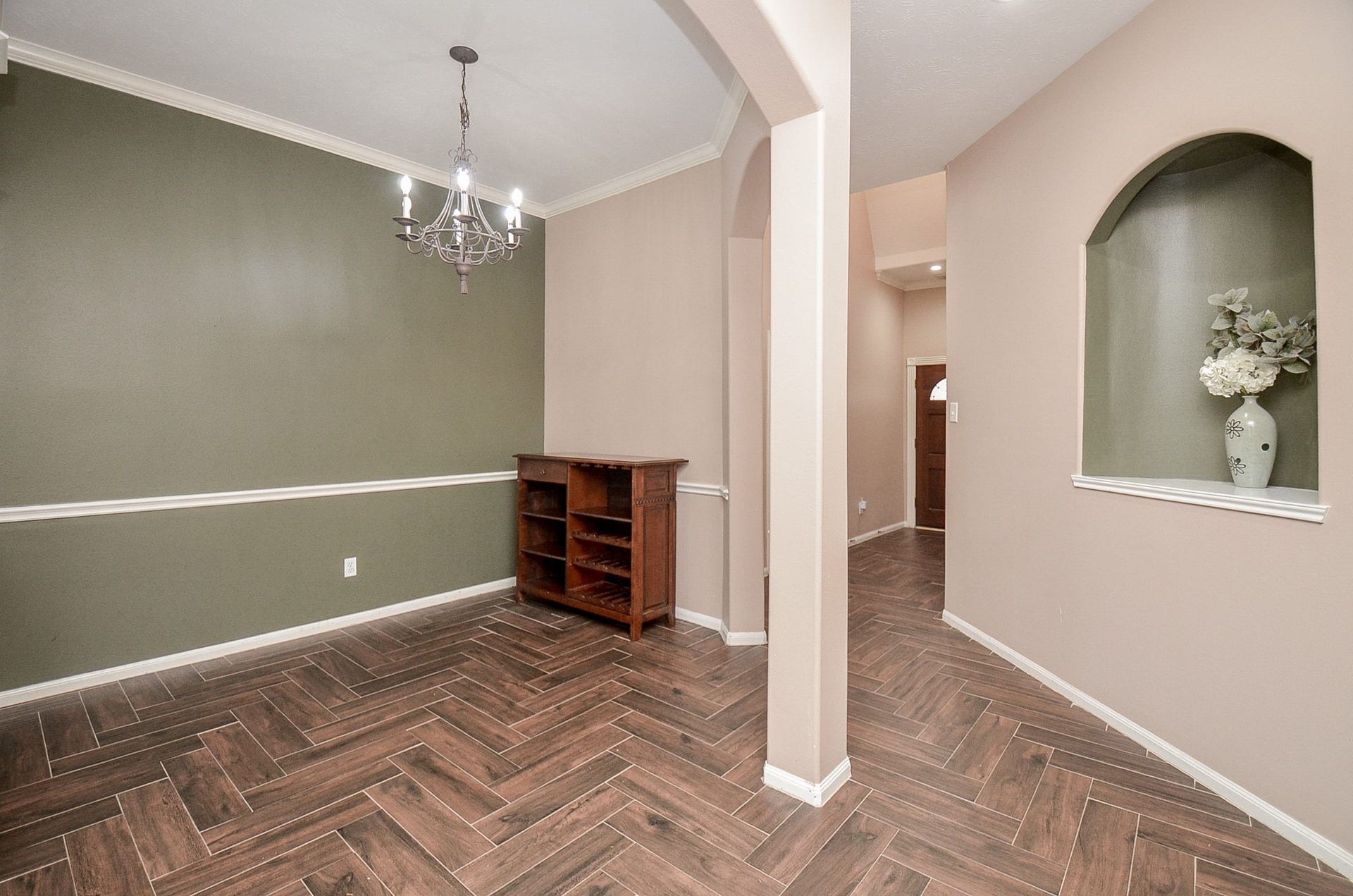 3706 Cane Lake Drive, Richmond, TX 77406 Elegant dining area with herringbone wood flooring, a classic chandelier, and a soothing two-tone wall palette. An arched entryway adds charm and character.