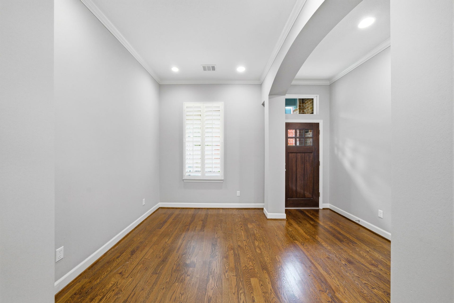 4926 Ella Boulevard, Houston, TX 77018 Bright entryway/study with hardwood floors, neutral walls, and wooden front door. The space features plantation shutters and recessed lighting, creating a welcoming atmosphere.