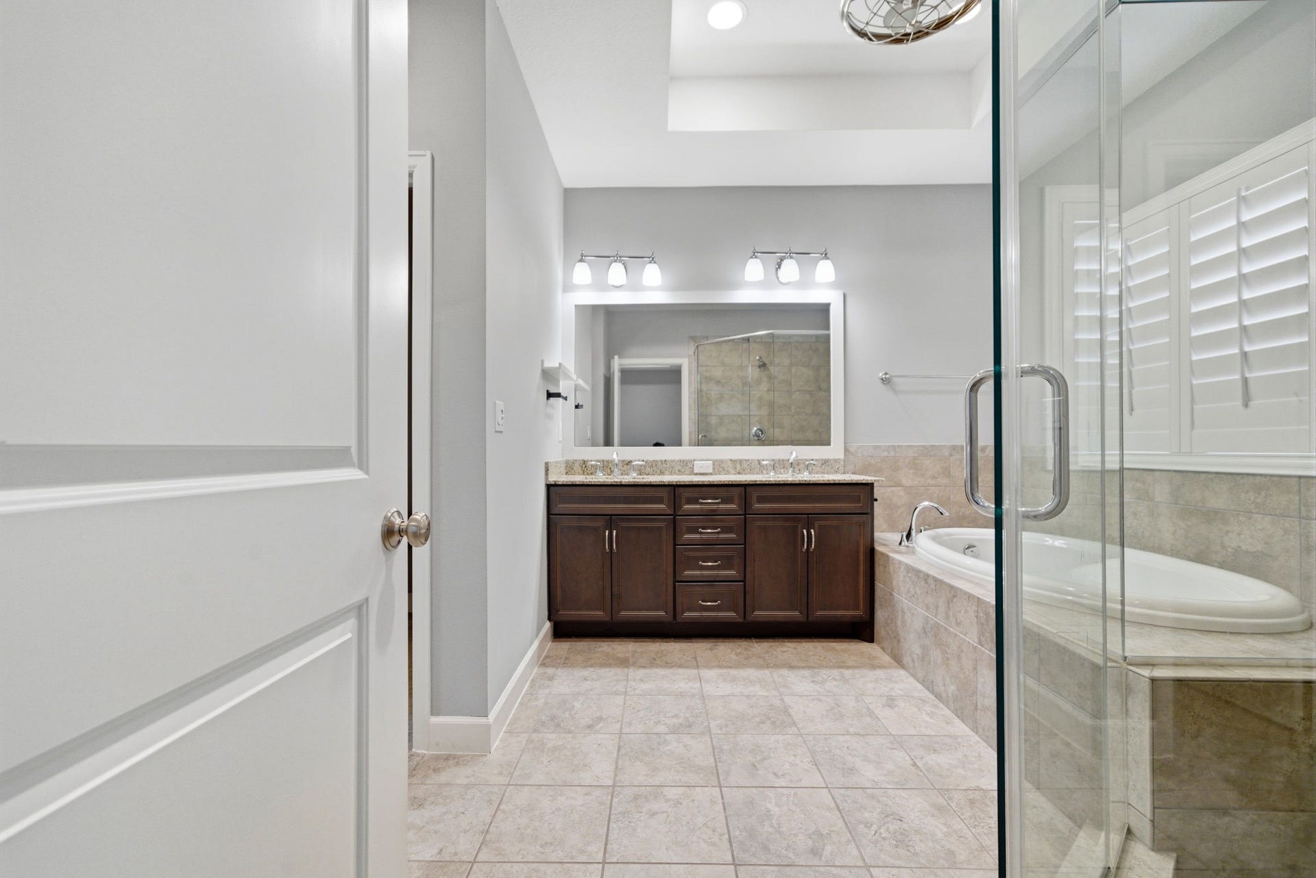 4926 Ella Boulevard, Houston, TX 77018 Primary bathroom features a glass-enclosed shower, a soaking tub, and dual vanities with ample storage. The neutral tile and modern lighting create a bright, elegant atmosphere.