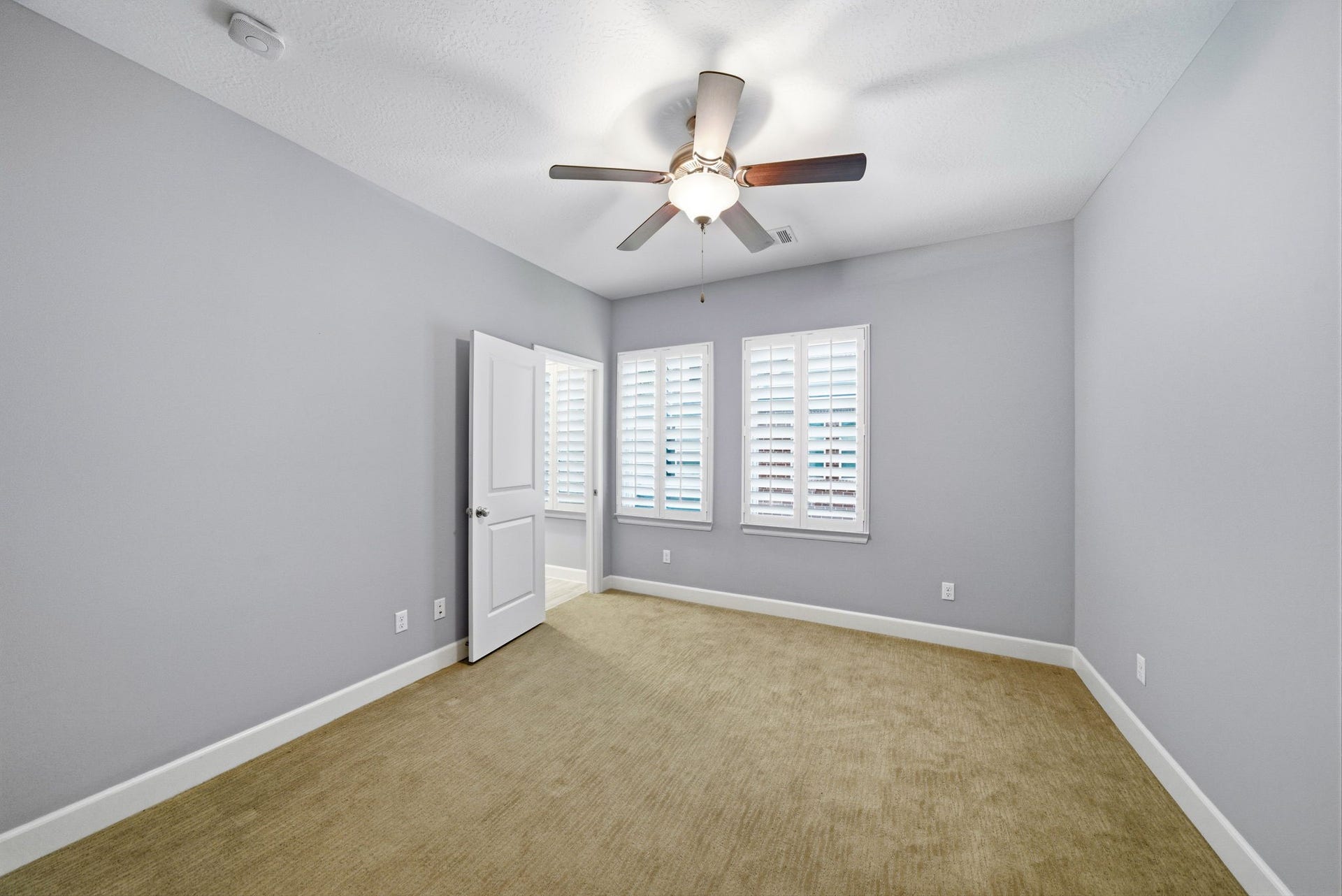 4926 Ella Boulevard, Houston, TX 77018 Bedroom features neutral carpet, plantation shutters and ceiling fan. It has large windows allowing natural light to brighten the space.