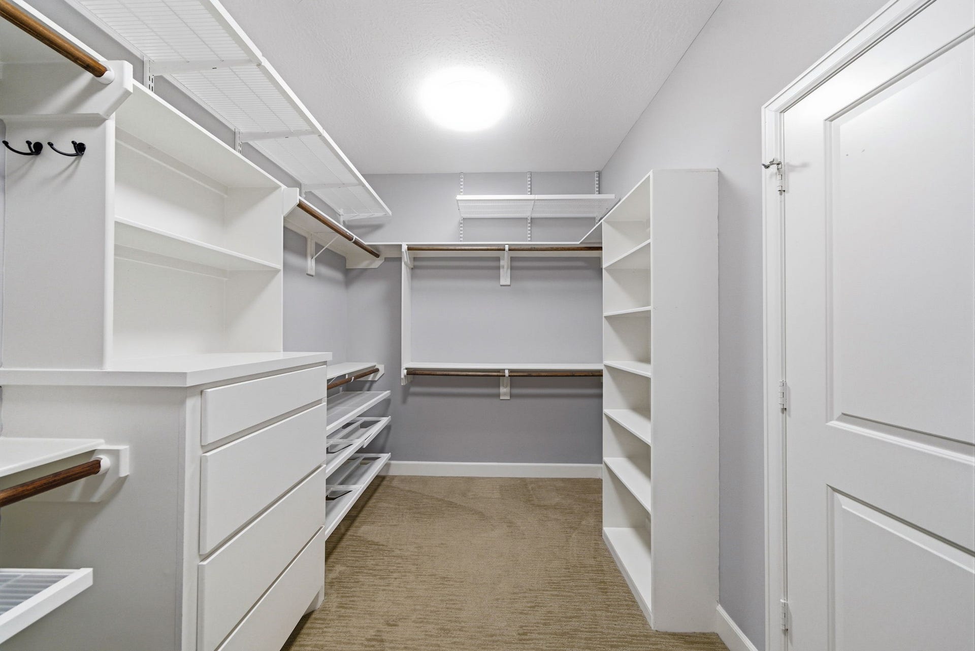 4926 Ella Boulevard, Houston, TX 77018 Primary Bedroom walk-in closet offers ample storage with built-in Custom Elfa closet system, drawers, and hanging rods, all in a bright, well-lit space with neutral carpeting.