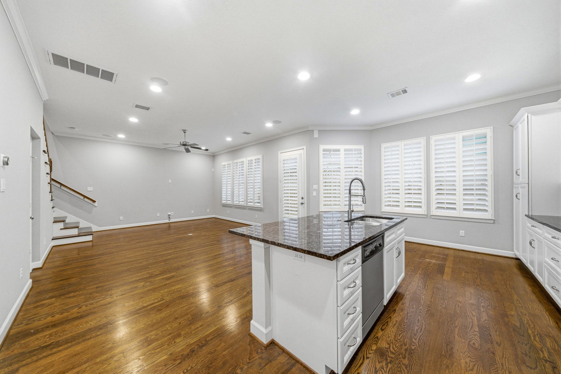 4926 Ella Boulevard, Houston, TX 77018 Spacious open-concept living area with hardwood floors and recessed lighting. It features a modern kitchen island with a granite countertop and stainless steel appliances. Large windows with plantation shutters provide ample natural light.