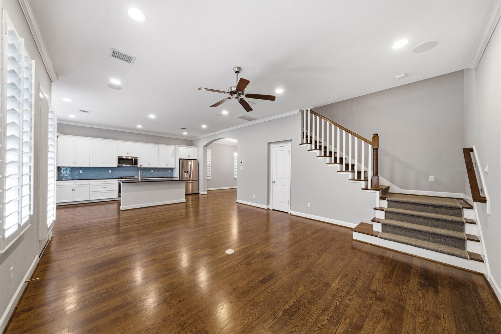 4926 Ella Boulevard, Houston, TX 77018 Spacious open-concept living area with hardwood floors, opens to a modern kitchen with stainless steel appliances, and a staircase leading to the upper level. Recessed lighting, ceiling fan and built-in speakers included.