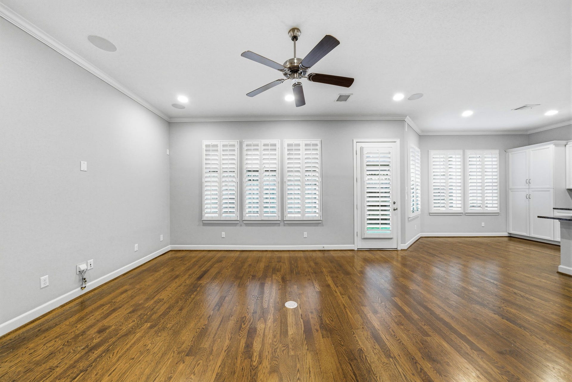 4926 Ella Boulevard, Houston, TX 77018 This spacious living room features hardwood floors, ample natural light from large windows with plantation shutters, a ceiling fan and built-in speakers. The open layout connects to the kitchen area, providing a versatile living space.