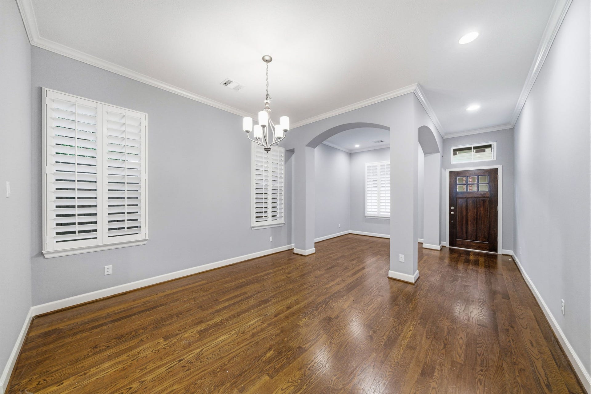 4926 Ella Boulevard, Houston, TX 77018 Formal dining room features hardwood floors and crown moulding. It has a modern chandelier, large windows with plantation shutters, and an arched entryway.