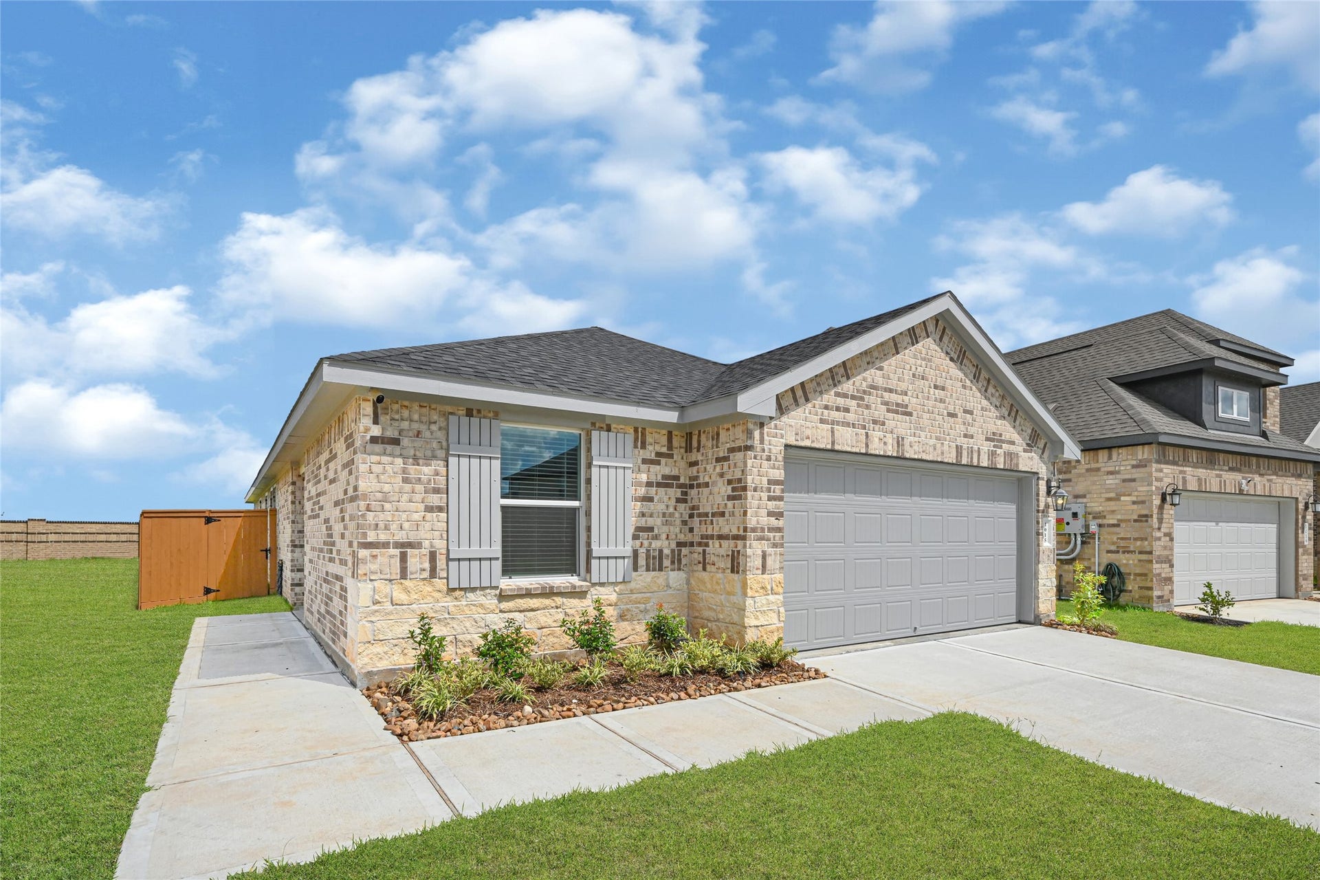 Charming brick home with a spacious two-car garage, well-maintained lawn, and a cozy front garden, nestled in a peaceful neighborhood.