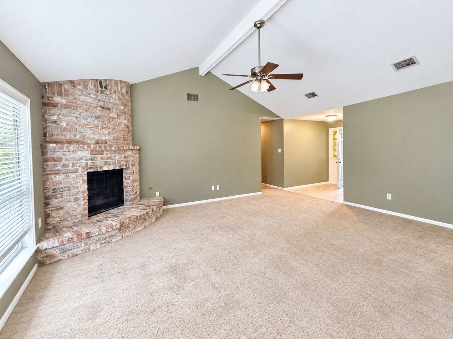 2026 Arcadia Drive, Sugar Land, TX 77498 Living Room with Fireplace: Inviting living room featuring a vaulted ceiling, charming brick fireplace, and an open, airy layout.