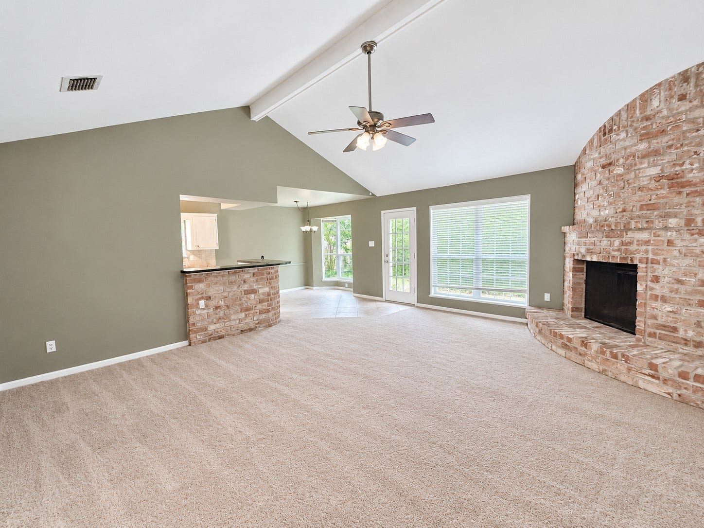 2026 Arcadia Drive, Sugar Land, TX 77498 Open Living Area: Spacious open-concept living area with vaulted ceilings, a brick fireplace, and seamless connection to the kitchen and dining spaces.