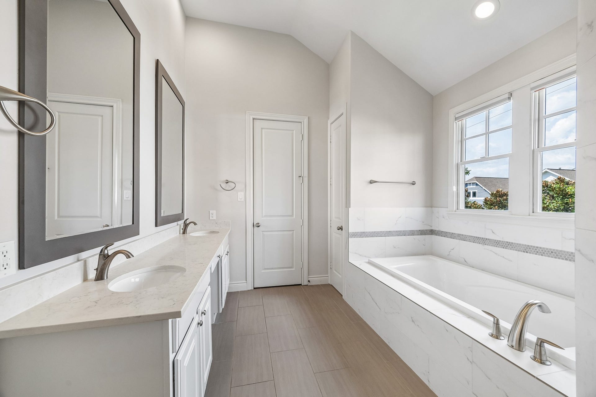 The primary 3rd floor ensuite bathroom has been updated (2021) offering a spacious soaking tub, quartz countertops, modern tile and elegant fixtures, all accented by natural light through large windows. One of 2 large walk in closet located  at the end.