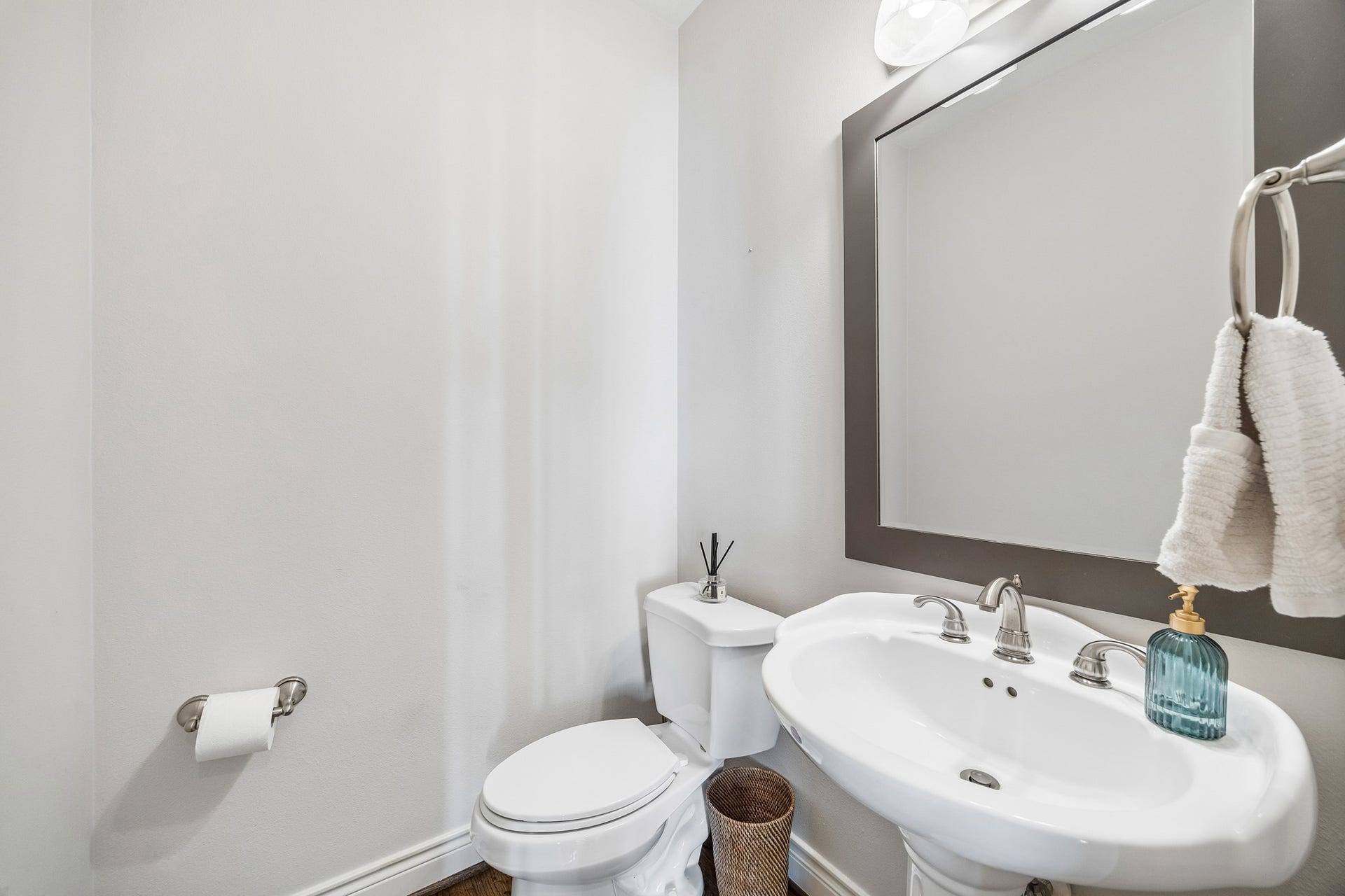 Bright and modern powder room features a sleek pedestal sink, elegant mirror and is conveniently located on the 2nd floor tucked away near the staircase.