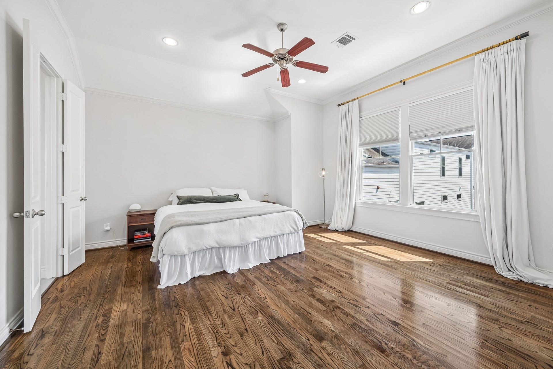 Ample sized Primary 3rd floor ensuite bedroom with gleaming hardwood floors, abundant natural light from large windows, and two separate walk in closets.