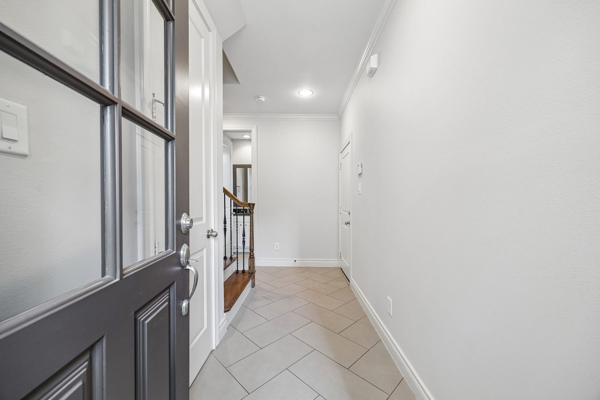 Inviting entryway with updated tile flooring (2021) leads to the garage on the right and a secondary bedroom suite on the left. The beautiful staircase leads to the 2nd floor. The door to the immediate left is a convenient coat closet.