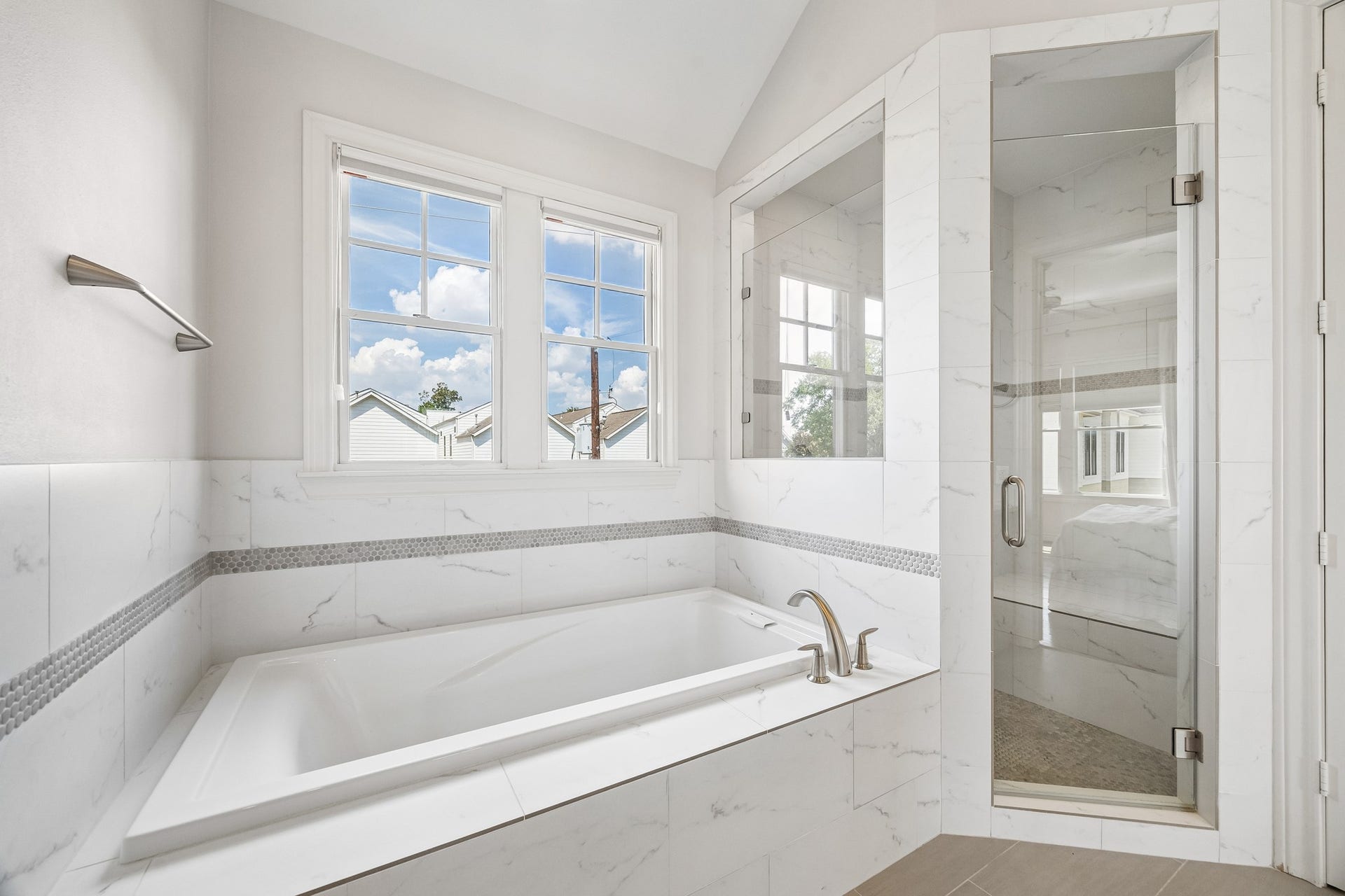 Consistent throughout the home, natural light floods the primary bathroom featuring the luxurious soaking tub and separate glass-enclosed shower