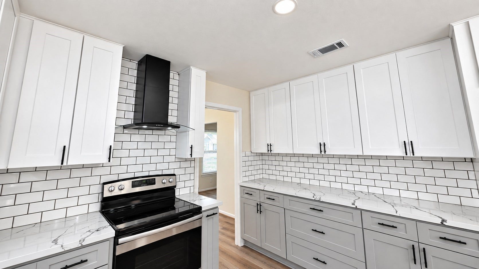 5527 Wigton Drive, Houston, TX 77096 Updated cooking area with stainless range, modern vent hood, subway tile, and generous cabinet storage.