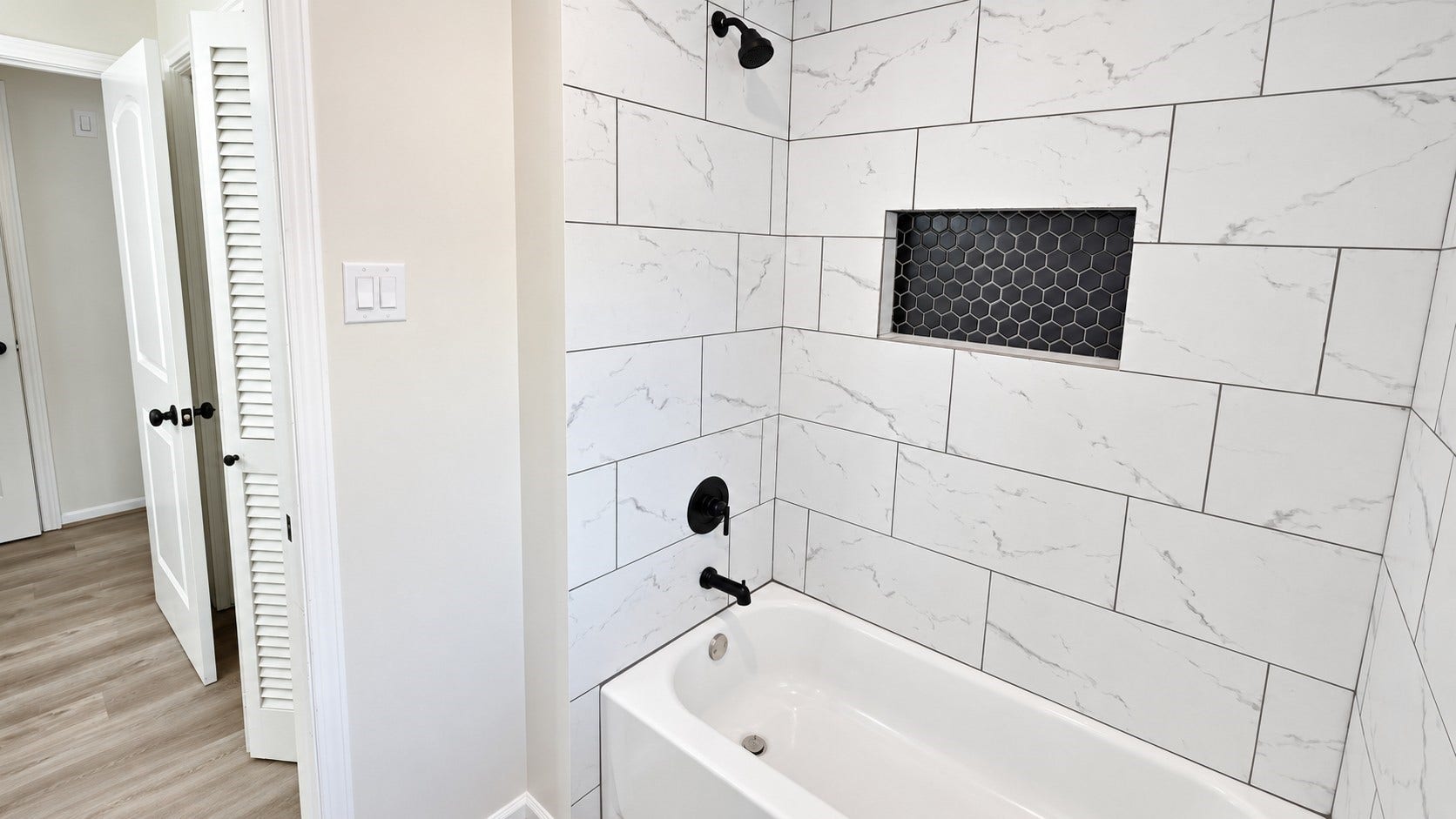 5527 Wigton Drive, Houston, TX 77096 Secondary bath includes a tub/shower combination surrounded by modern large-format tile and a built-in niche.