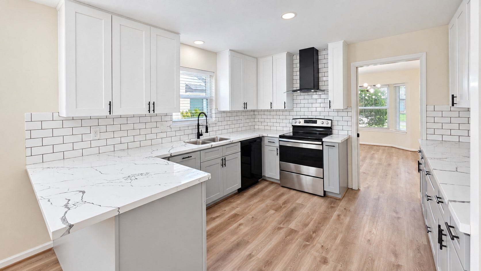 5527 Wigton Drive, Houston, TX 77096 Updated kitchen features crisp white cabinetry, contrasting lower cabinets, black hardware, and stainless appliances.