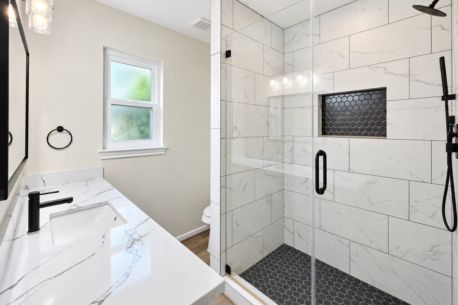 5527 Wigton Drive, Houston, TX 77096 Primary bath features a striking glass-enclosed walk-in shower with oversized tile, niche, and matte-black fixtures.