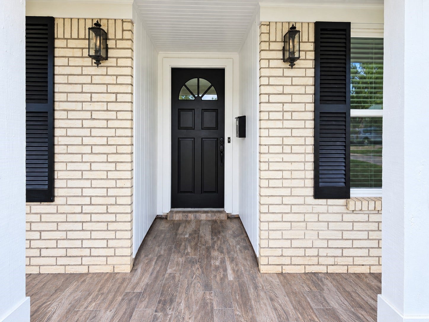 5527 Wigton Drive, Houston, TX 77096 Covered front porch leads to a striking black entry door framed by classic brick and black accents.
