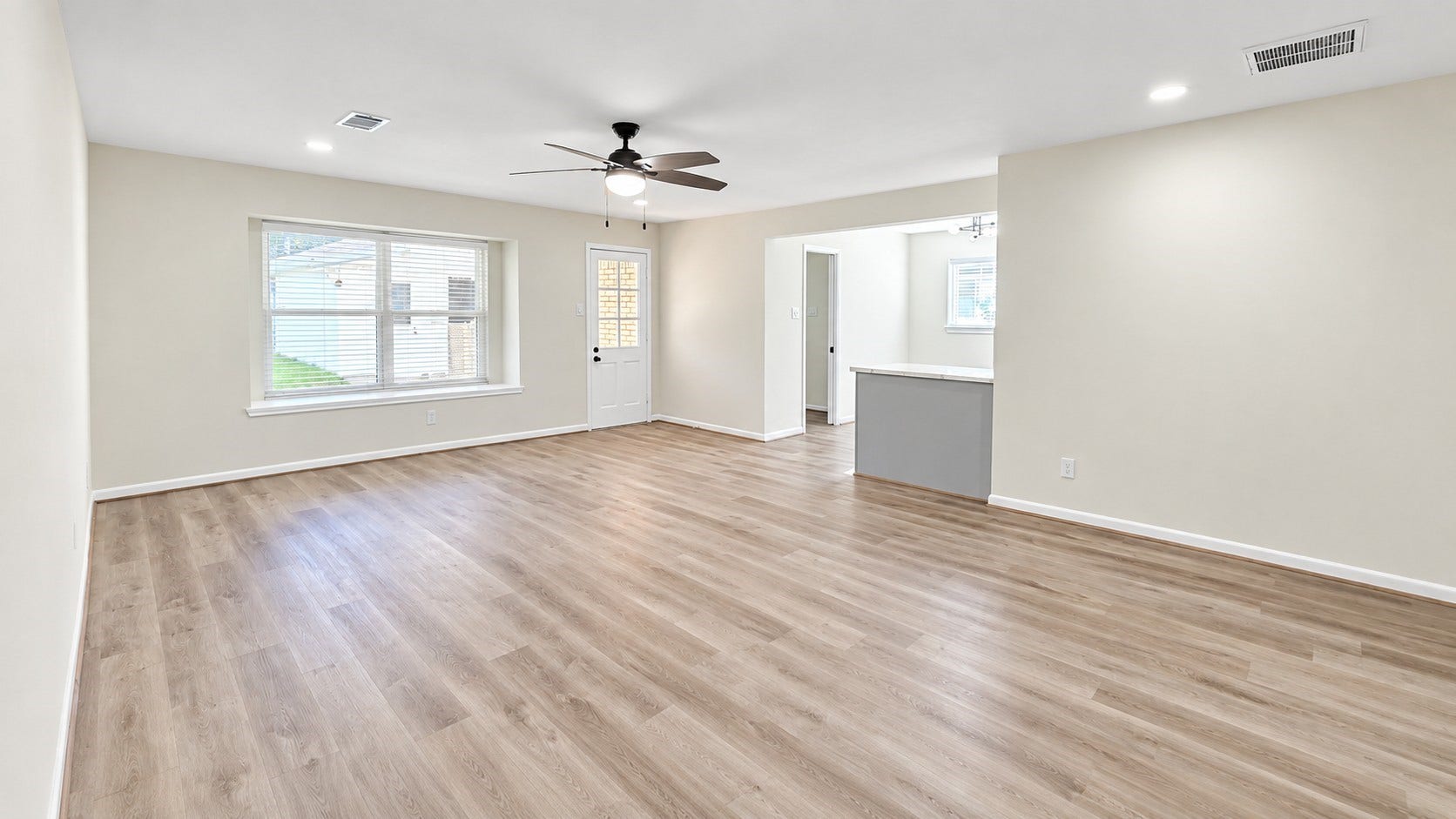 5527 Wigton Drive, Houston, TX 77096 Expansive living area with updated flooring, recessed lighting, ceiling fan, and an open connection to the kitchen.