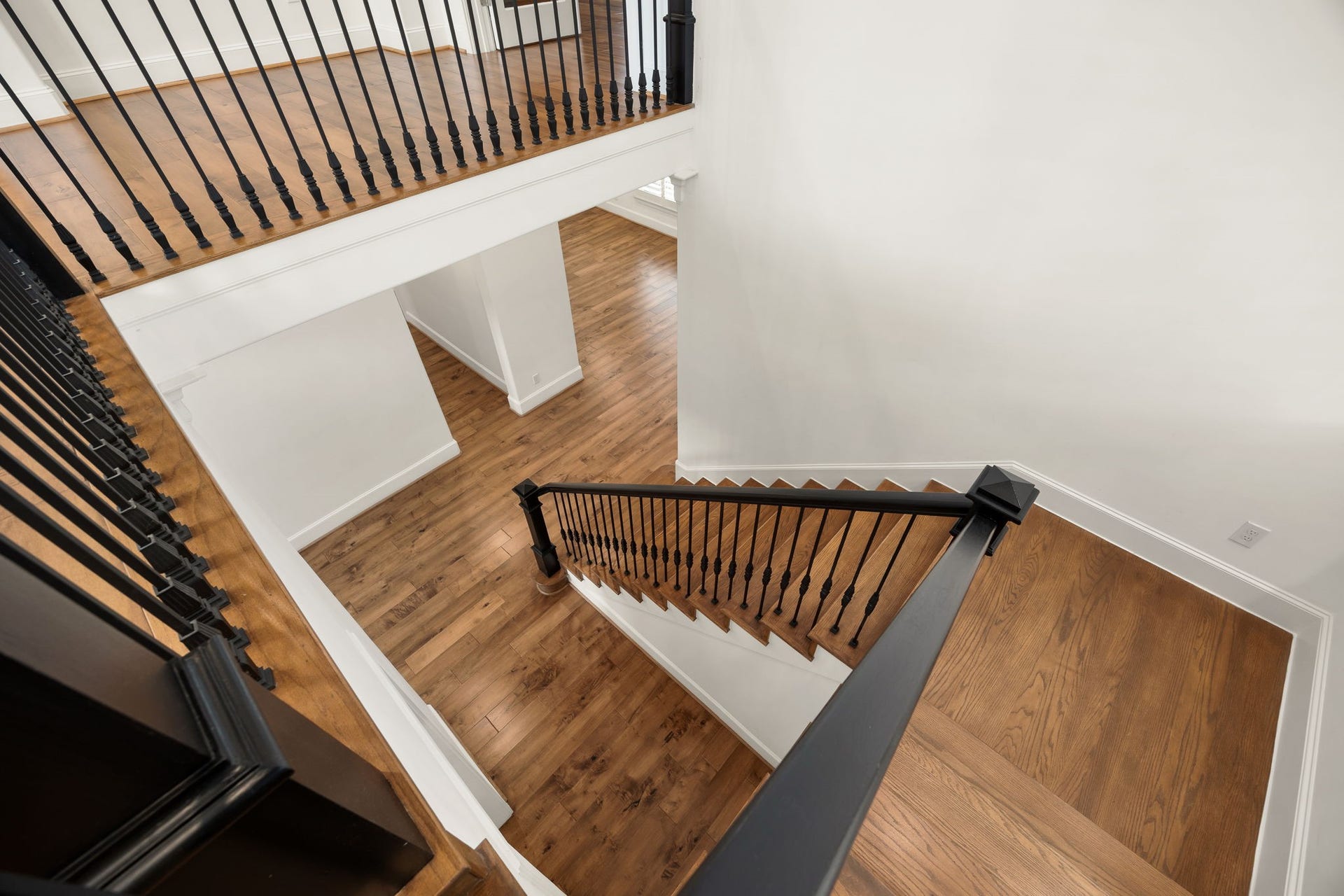 The staircase makes a beautiful statement with rich wood treads, classic black iron balusters, and crisp white trim. Its open design adds a sense of grandeur while creating an elegant connection between the home's two levels.