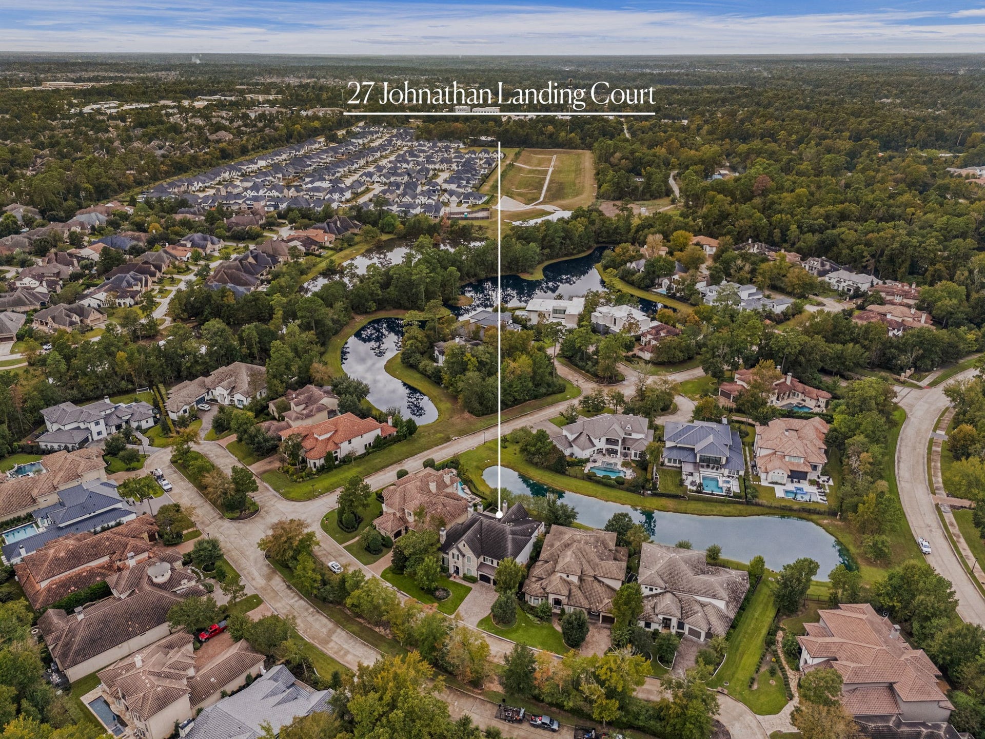 An impressive birds eye view showcases 27 Johnathan Landing Court, beautifully positioned among scenic lakes, mature trees, and elegant homes throughout the community. Its picturesque surroundings create a stunning backdrop for this exceptional home, offering a wonderful blend of privacy, natural beauty, and upscale living.