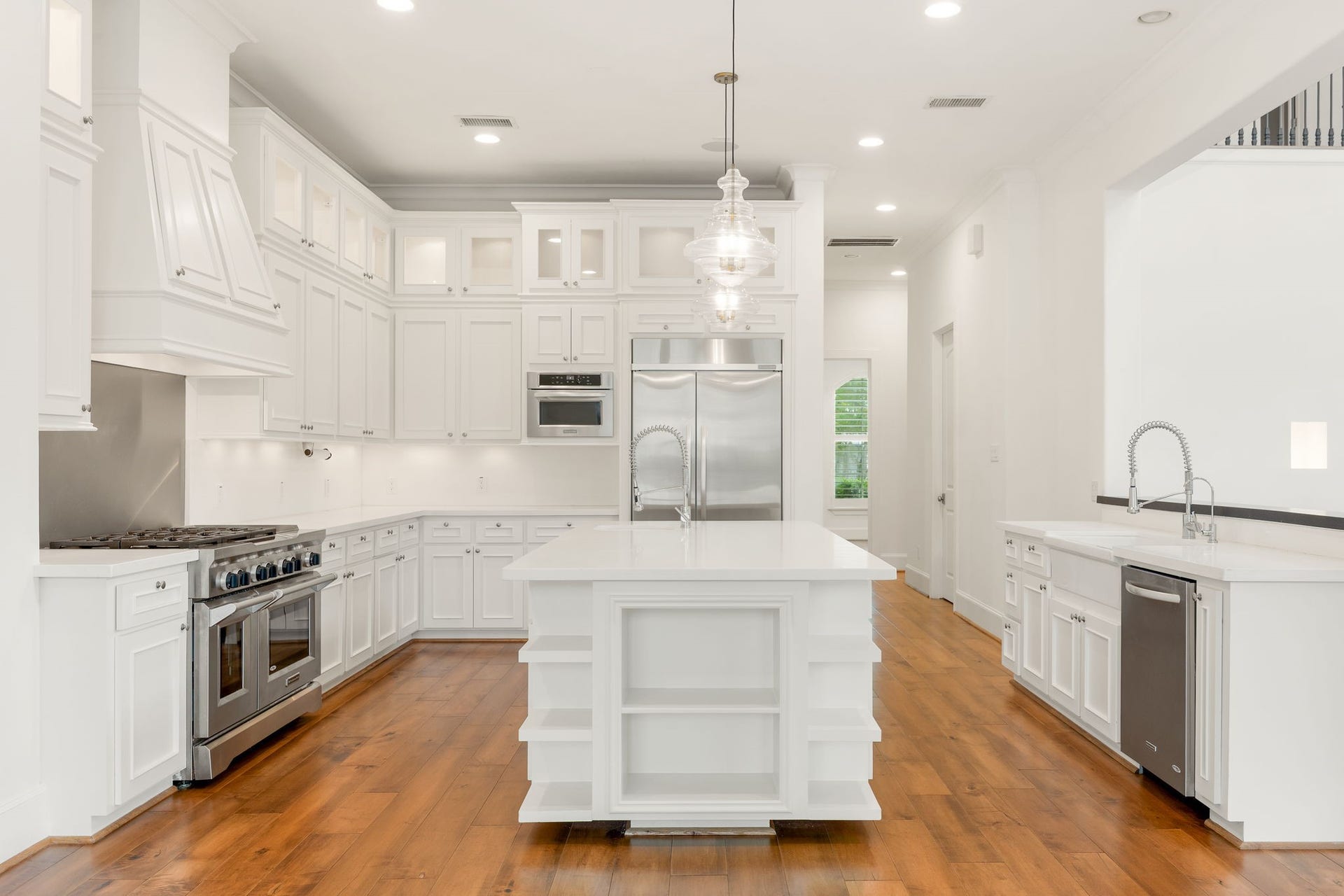 This stunning kitchen is designed to be the heart of the home, featuring beautifully detailed white cabinetry, elegant quartz countertops, and an expansive island that invites you to gather and connect! Professional grade stainless steel appliances, double ovens, a gas cooktop, and warm wood flooring bring together timeless sophistication and everyday comfort, creating a space where everything from slow morning coffees to memorable dinner parties feels special.