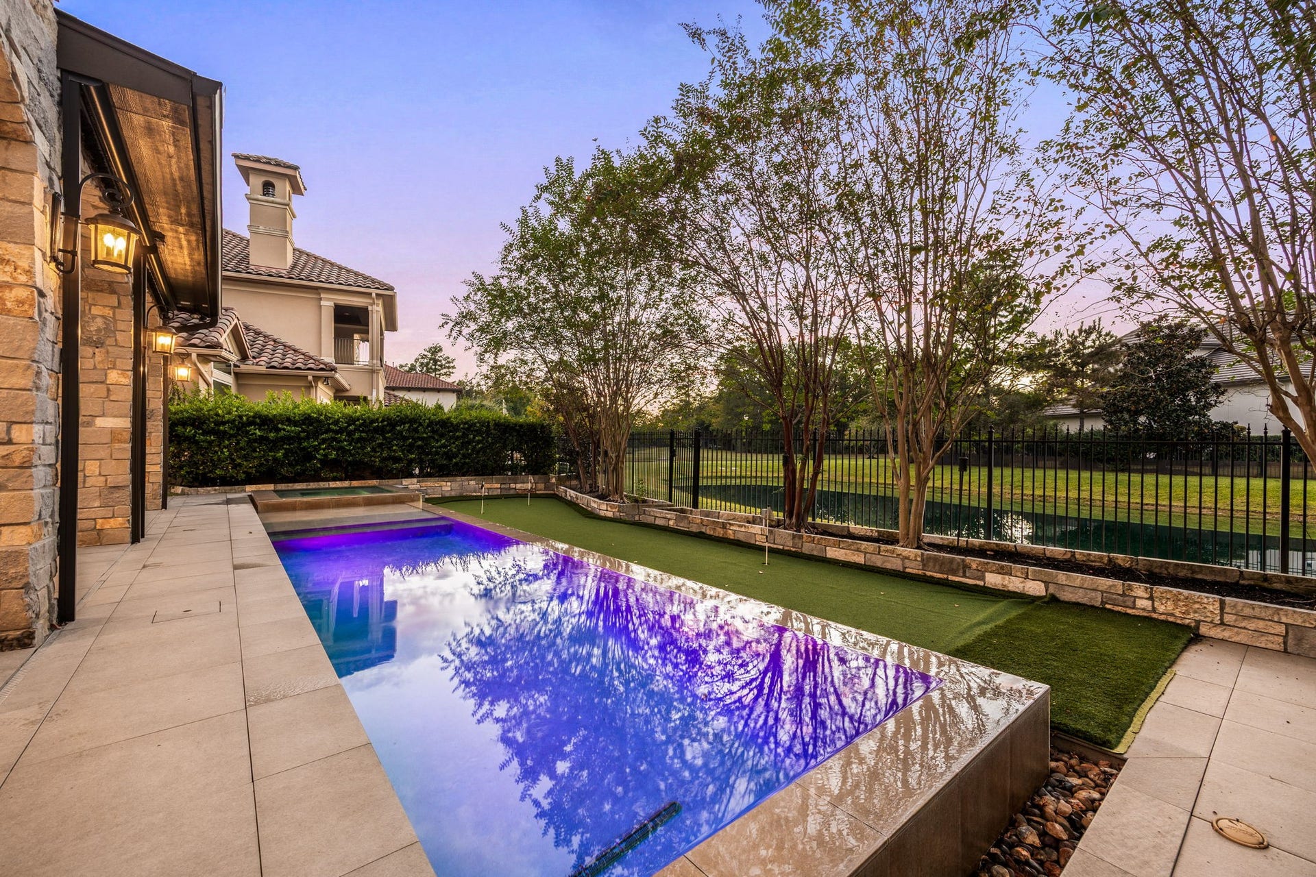 Designed for effortless outdoor enjoyment, the private pool and spa are framed by elegant stone coping, expansive paved decking, and lush landscaping. The adjacent putting green and tranquil lake views create a serene backyard retreat, perfect for leisurely afternoons and relaxing evenings at home.