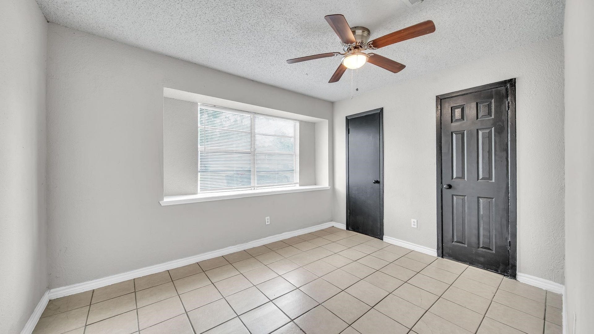10902 Jutland Road, Houston, TX 77048 The primary suite offers a serene retreat, featuring elegant tile flooring, a ceiling fan with integrated lighting and a spacious walk-in closet with ample storage for an organized wardrobe.