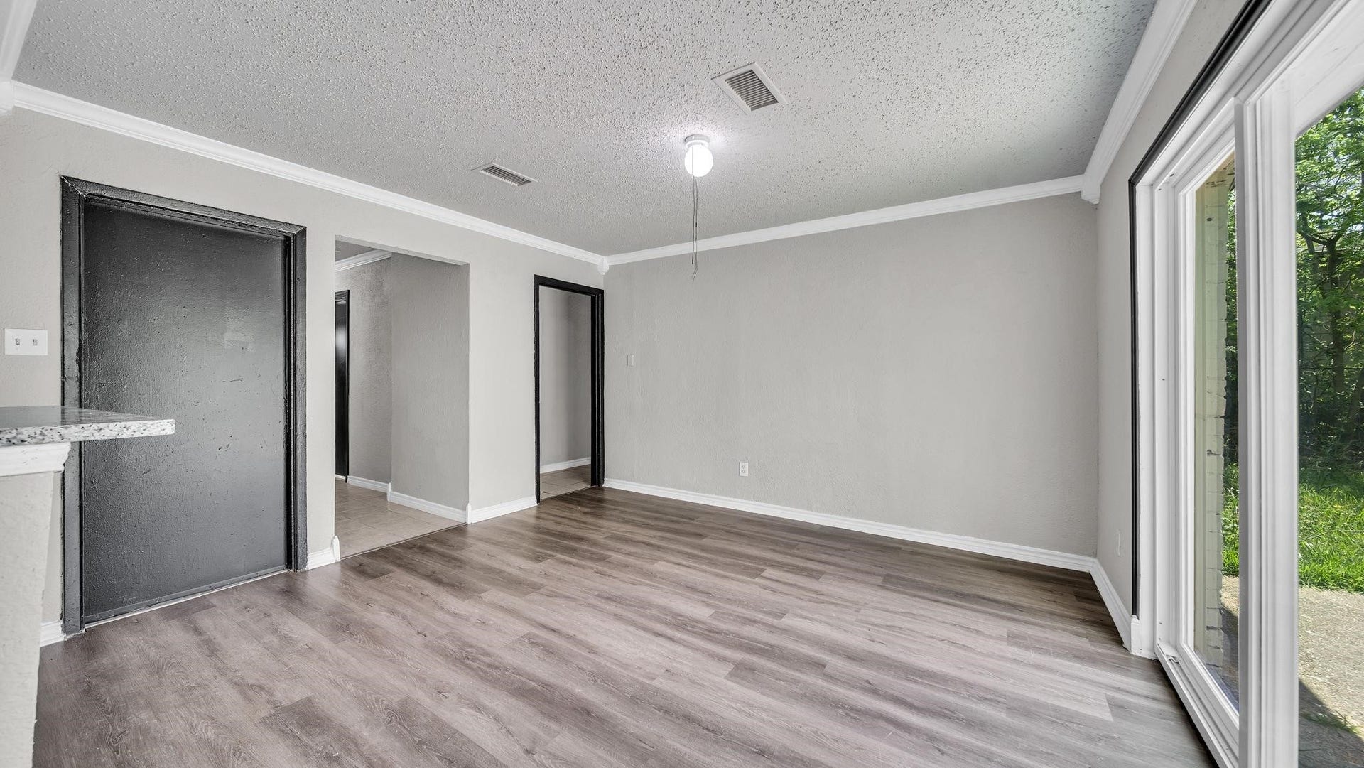 10902 Jutland Road, Houston, TX 77048 Wide-plank luxury vinyl flooring brings warmth and sophistication to the living room, while elegant crown molding adds a timeless architectural touch. A spacious, inviting setting that beautifully balances comfort with understated luxury.