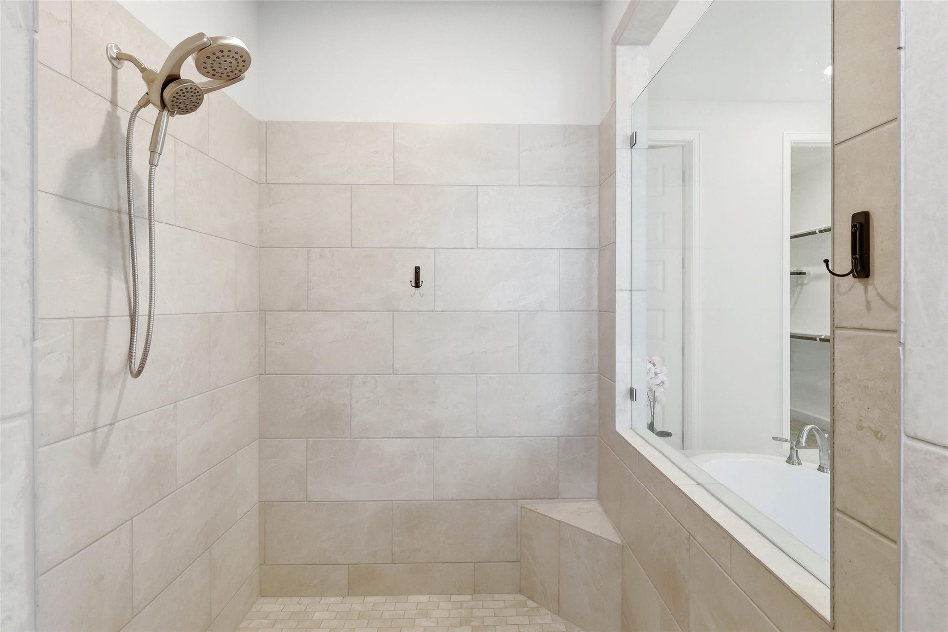 30135 Gold Finch Place, Fulshear, TX 77441 The oversized walk-in shower is beautifully finished with floor-to-ceiling tile, a built-in bench, recessed niche, and large picture window that fills the space with natural light while maintaining privacy.