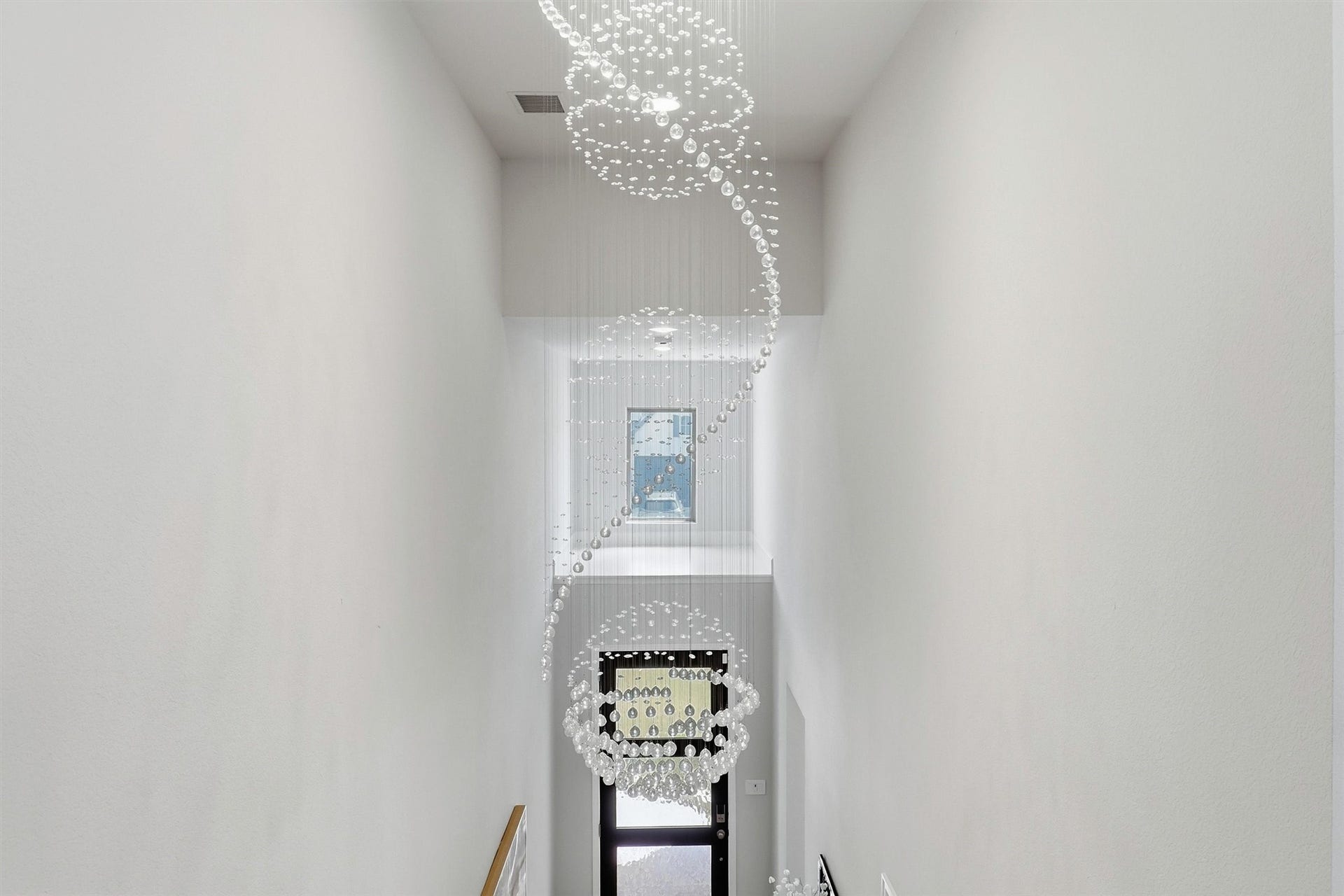 30135 Gold Finch Place, Fulshear, TX 77441 A breathtaking multi-story crystal chandelier creates a dramatic first impression, cascading gracefully through the soaring foyer and serving as a stunning architectural centerpiece visible from both levels of the home.
