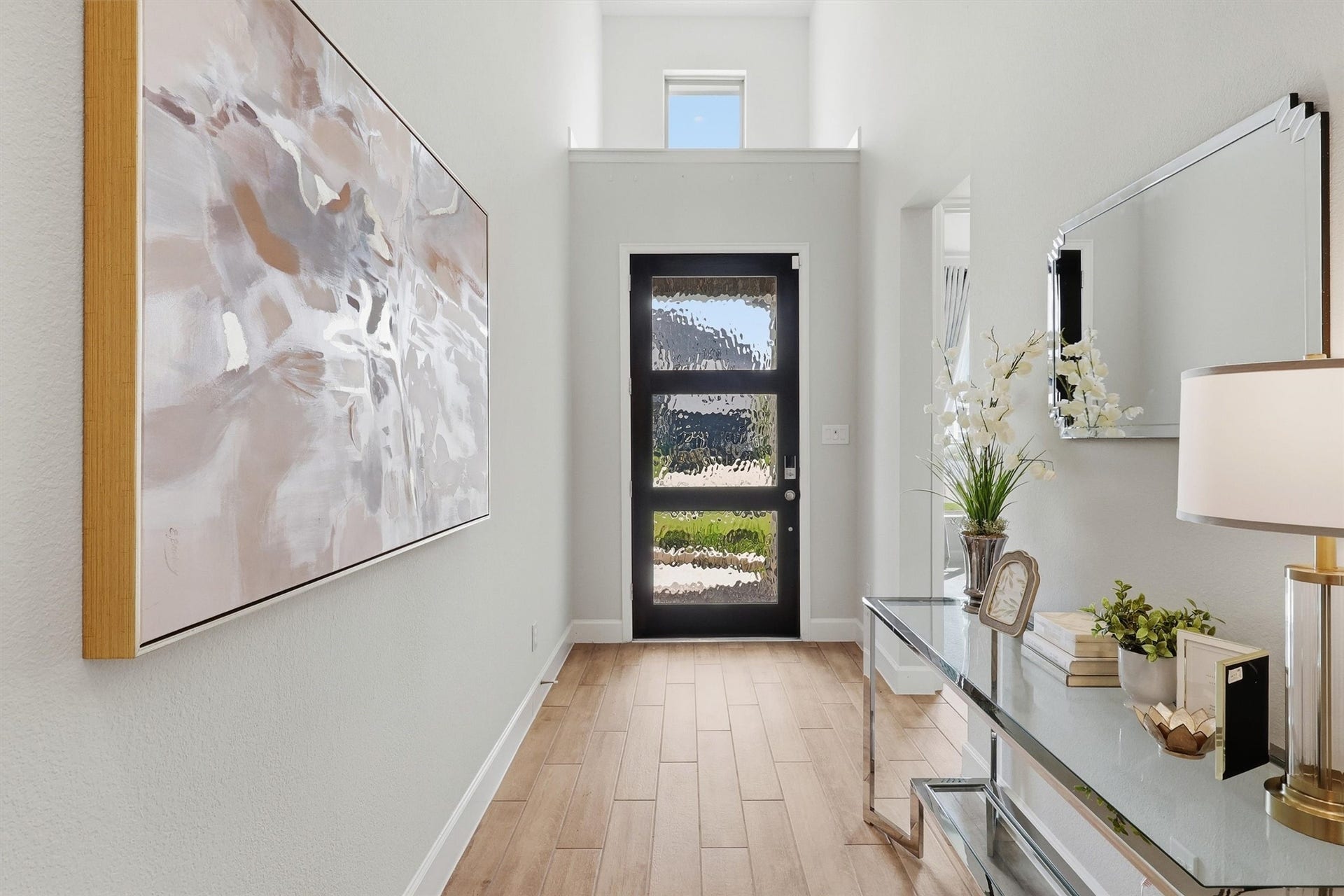 30135 Gold Finch Place, Fulshear, TX 77441 An impressive two-story foyer creates a memorable first impression with soaring ceilings, abundant natural light, designer wood-look tile flooring, and a striking modern front door featuring textured glass for both style and privacy.