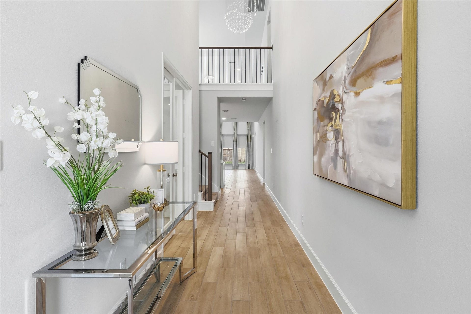 30135 Gold Finch Place, Fulshear, TX 77441 This impressive foyer offers a stunning first impression with soaring ceilings, designer lighting, elegant wood-look tile flooring, and an open sightline that draws your eye toward the spacious living areas beyond.