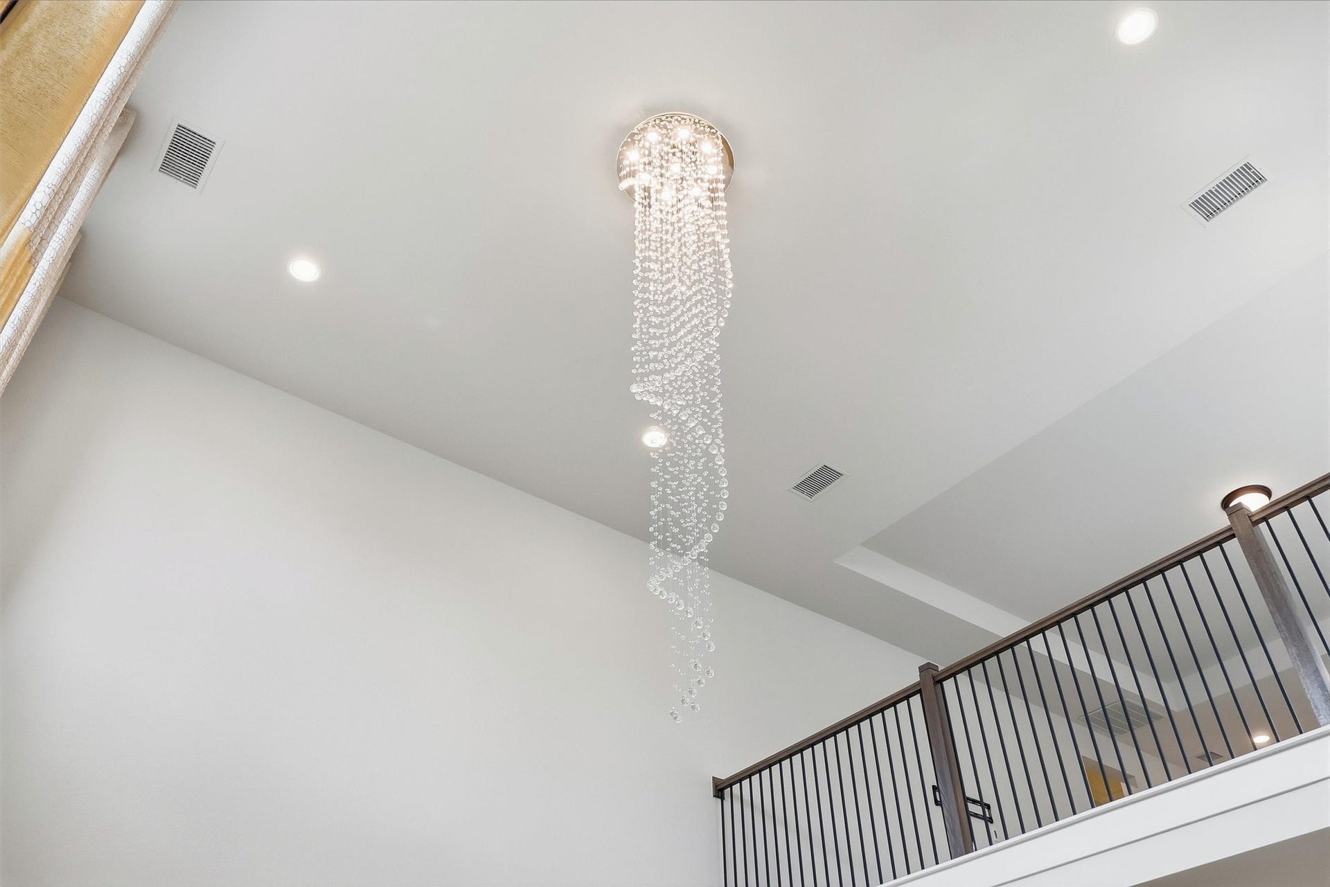 30135 Gold Finch Place, Fulshear, TX 77441 A breathtaking multi-story crystal chandelier creates a dramatic first impression, cascading gracefully through the soaring foyer and serving as a stunning architectural centerpiece visible from both levels of the home.