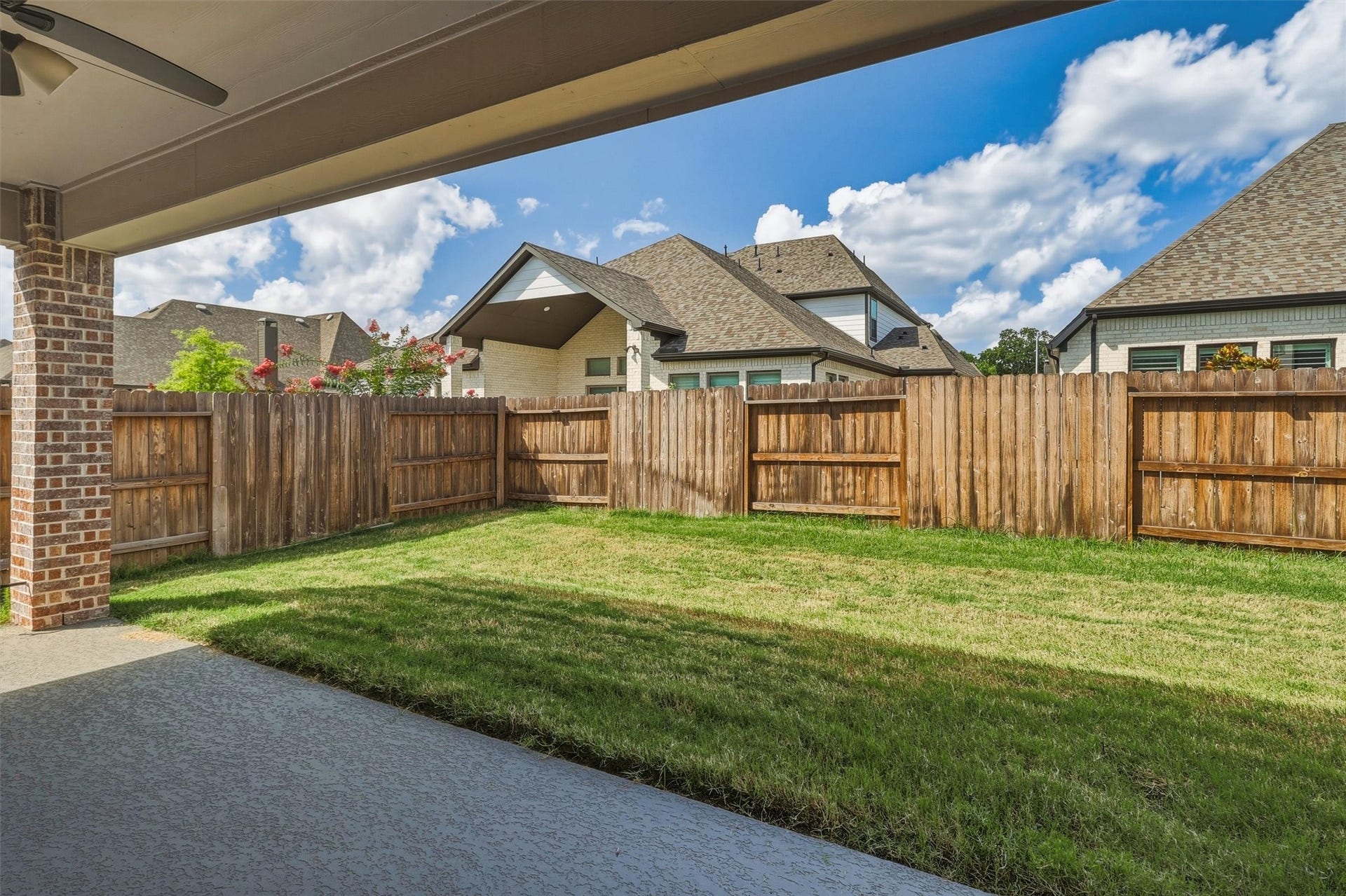 30135 Gold Finch Place, Fulshear, TX 77441 Another patio perspective showcases the home's spacious backyard and covered entertaining area. The private fenced yard provides an ideal setting for relaxing, dining outdoors, or enjoying time with family and friends.