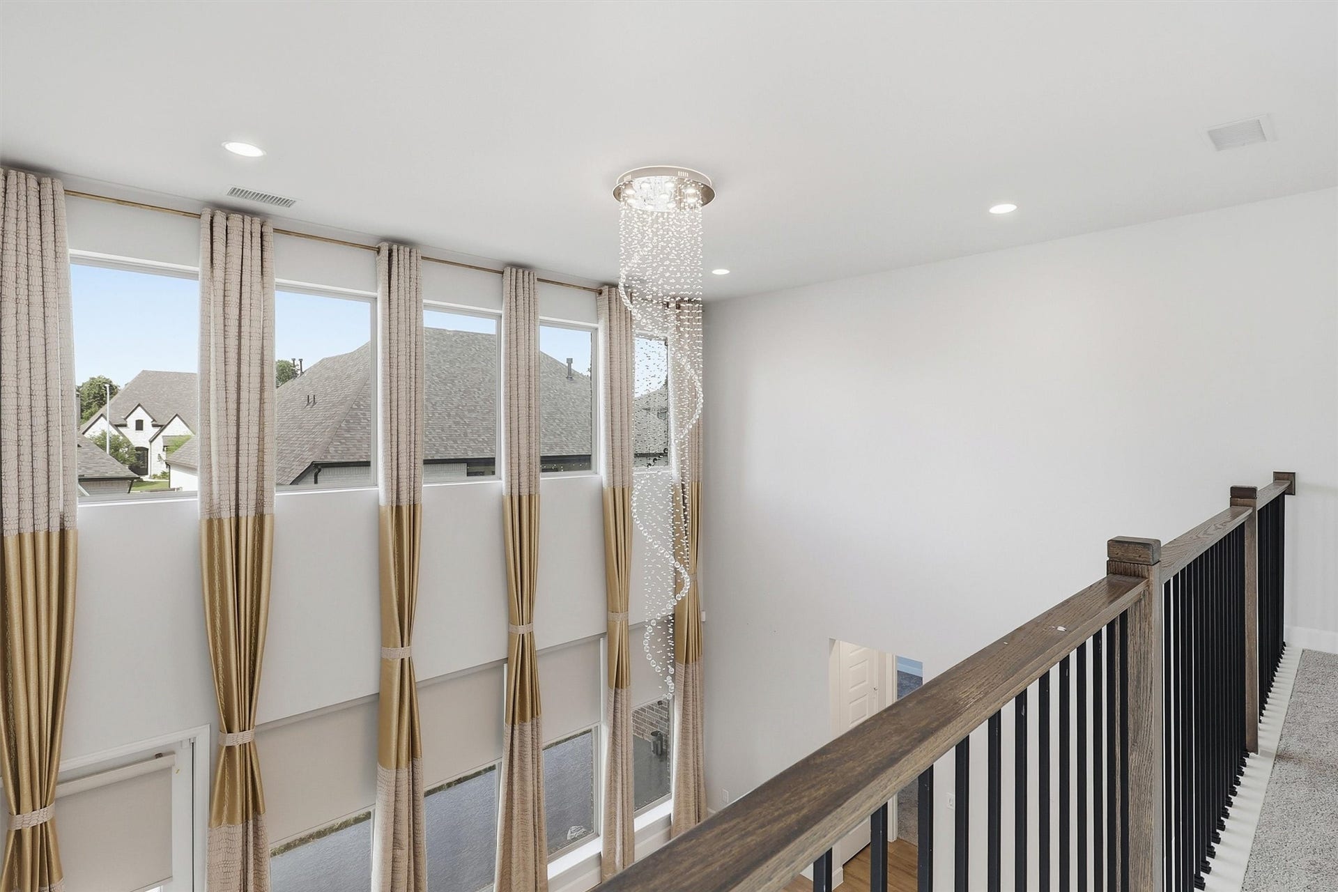 30135 Gold Finch Place, Fulshear, TX 77441 From the upstairs landing, oversized windows flood the home with natural light while the dramatic crystal chandelier provides an elegant focal point that beautifully connects both levels of the residence.