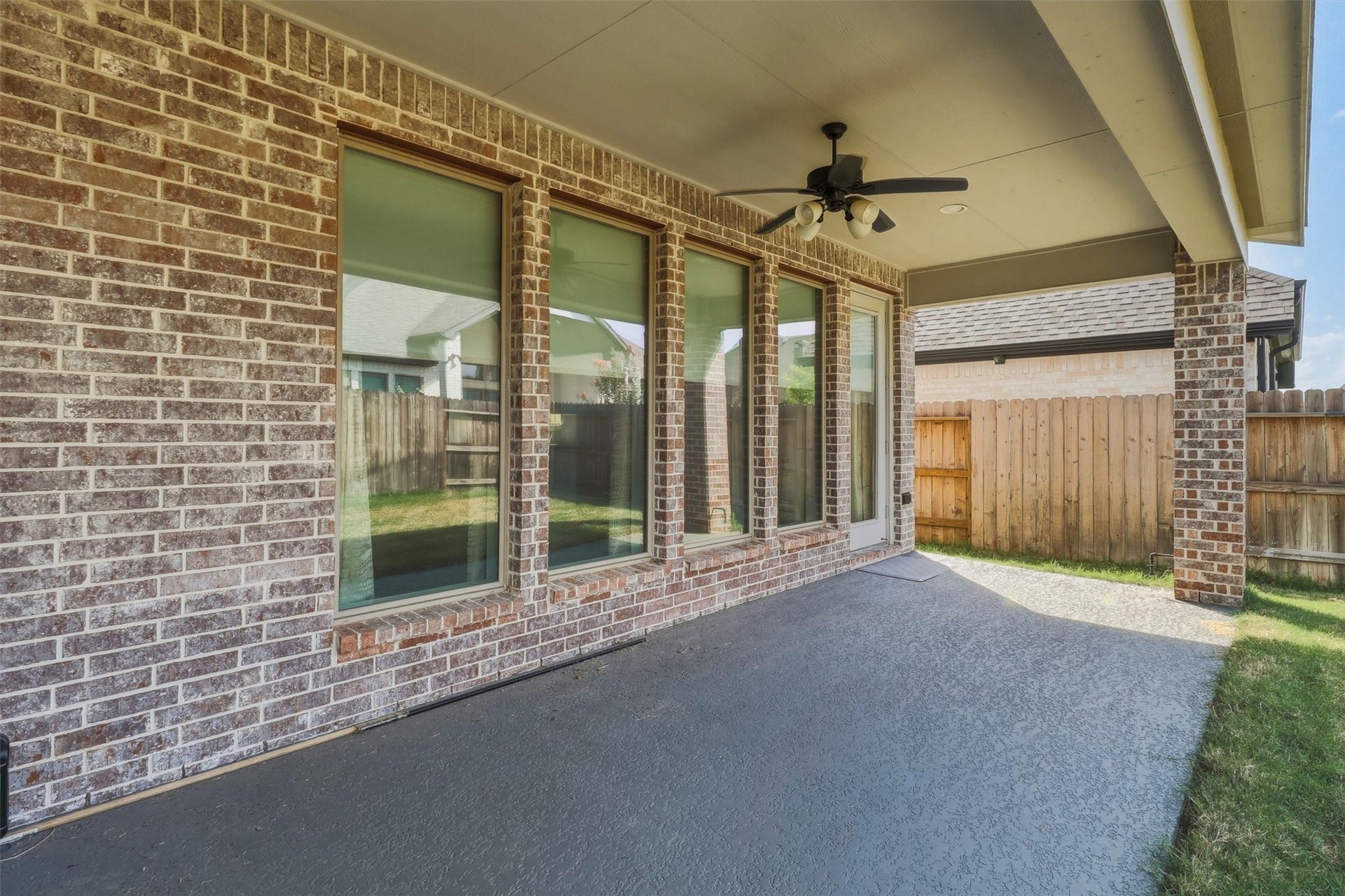 30135 Gold Finch Place, Fulshear, TX 77441 Enjoy shaded outdoor living beneath the spacious covered patio, complete with a ceiling fan for added comfort. Multiple rear windows provide abundant natural light indoors while maintaining seamless access to the backyard.