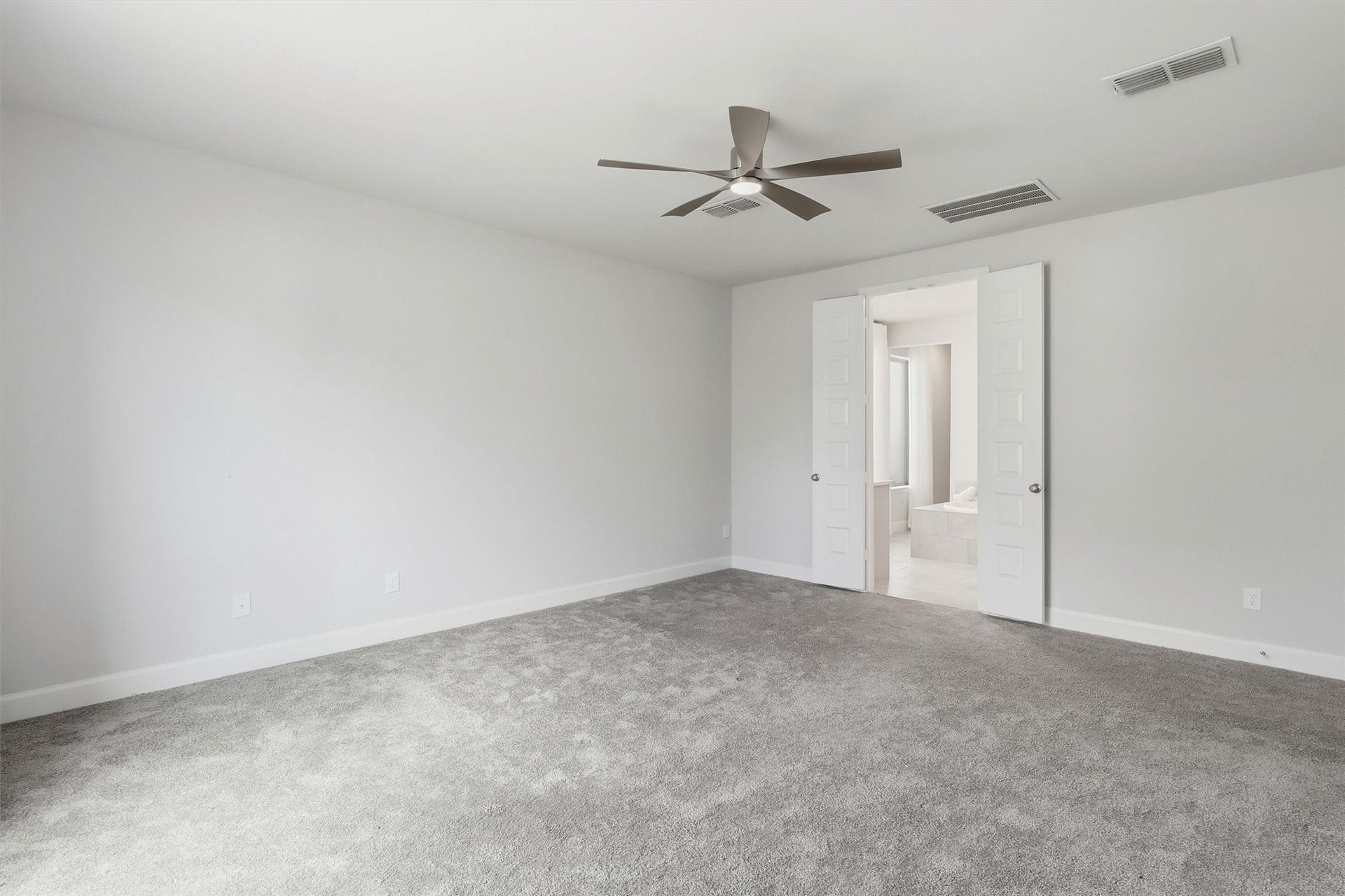 30135 Gold Finch Place, Fulshear, TX 77441 From this perspective, the primary bedroom showcases its impressive scale and thoughtful layout. Double doors lead directly into the luxurious ensuite bath, creating a seamless private retreat.