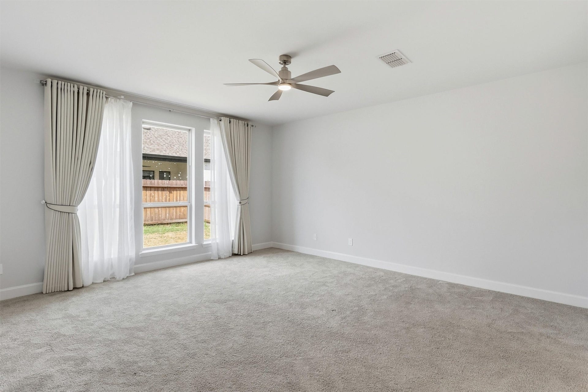 30135 Gold Finch Place, Fulshear, TX 77441 The expansive primary suite offers a peaceful retreat with plush carpeting, a designer ceiling fan, oversized windows dressed with elegant custom drapery, and plenty of space for a complete bedroom suite and sitting area.