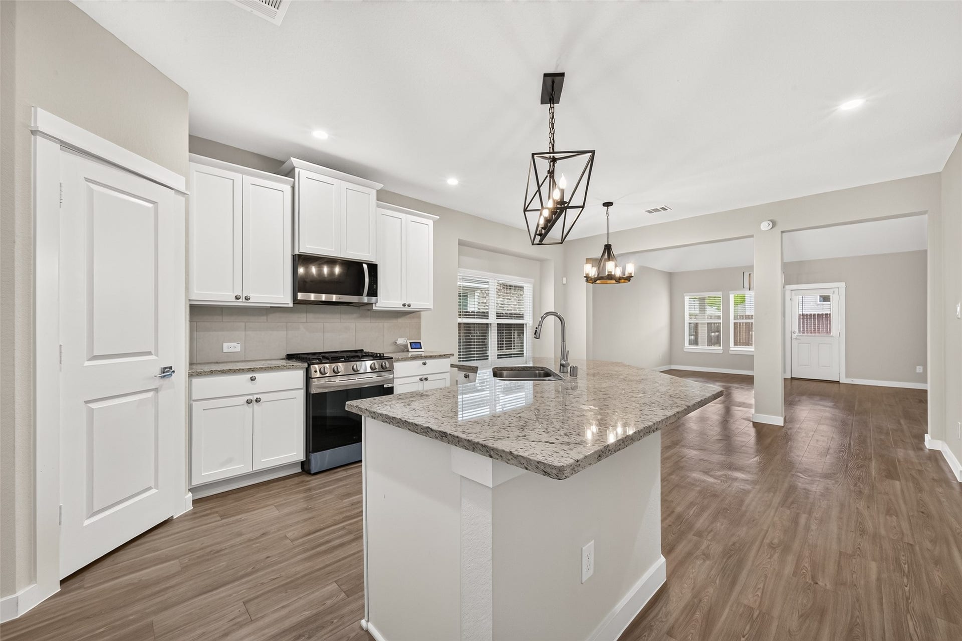 32922 Ruthie Dean Drive, Fulshear, TX 77423 White cabinetry, granite countertops, stainless steel appliances, and upgraded lighting complement this bright kitchen.