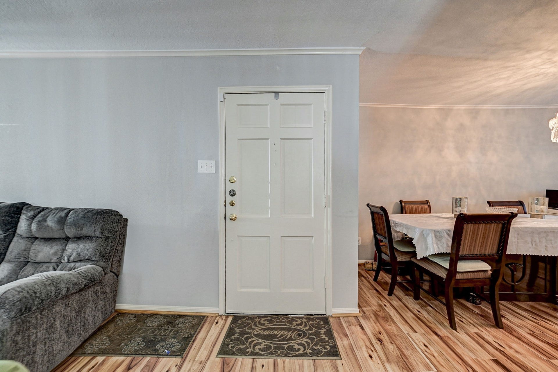 7900 Westheimer Road, #202, Houston, TX 77063 Inviting living space featuring a cozy gray sofa and an adjacent dining area with a stylish table setting, enhanced by warm wood flooring and soft lighting.